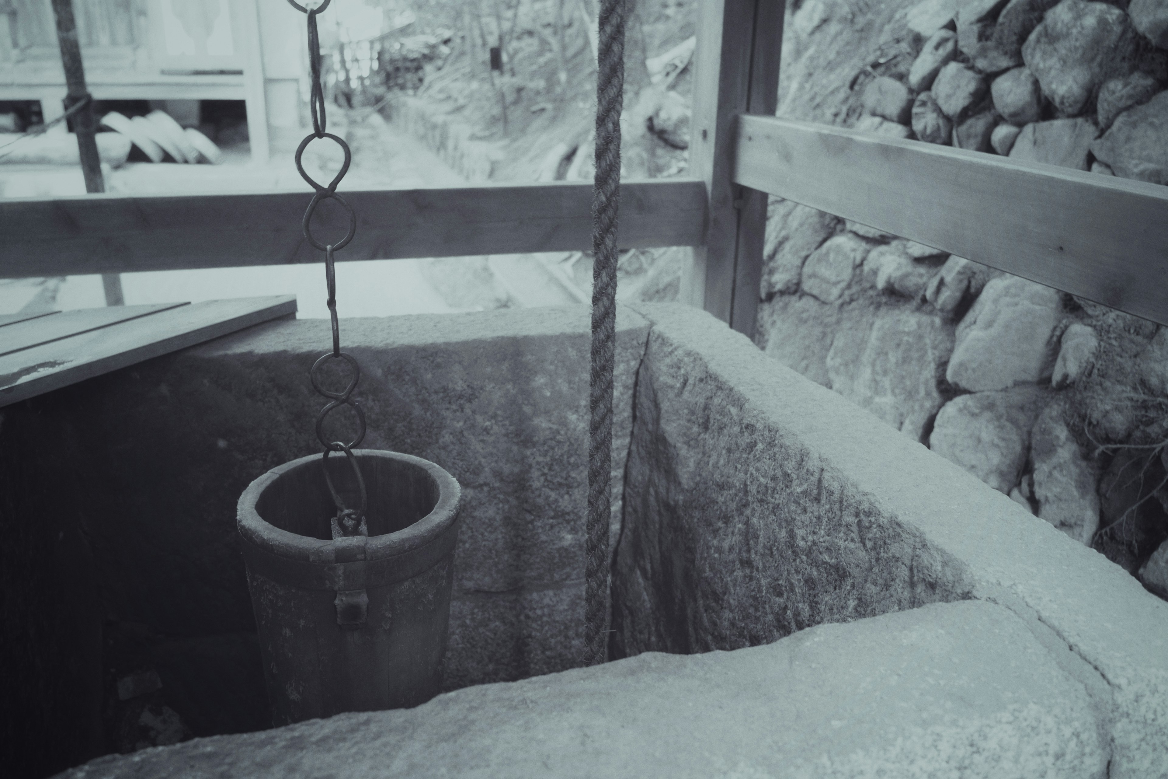 Foto en blanco y negro de un viejo pozo con paredes de piedra y estructura de madera