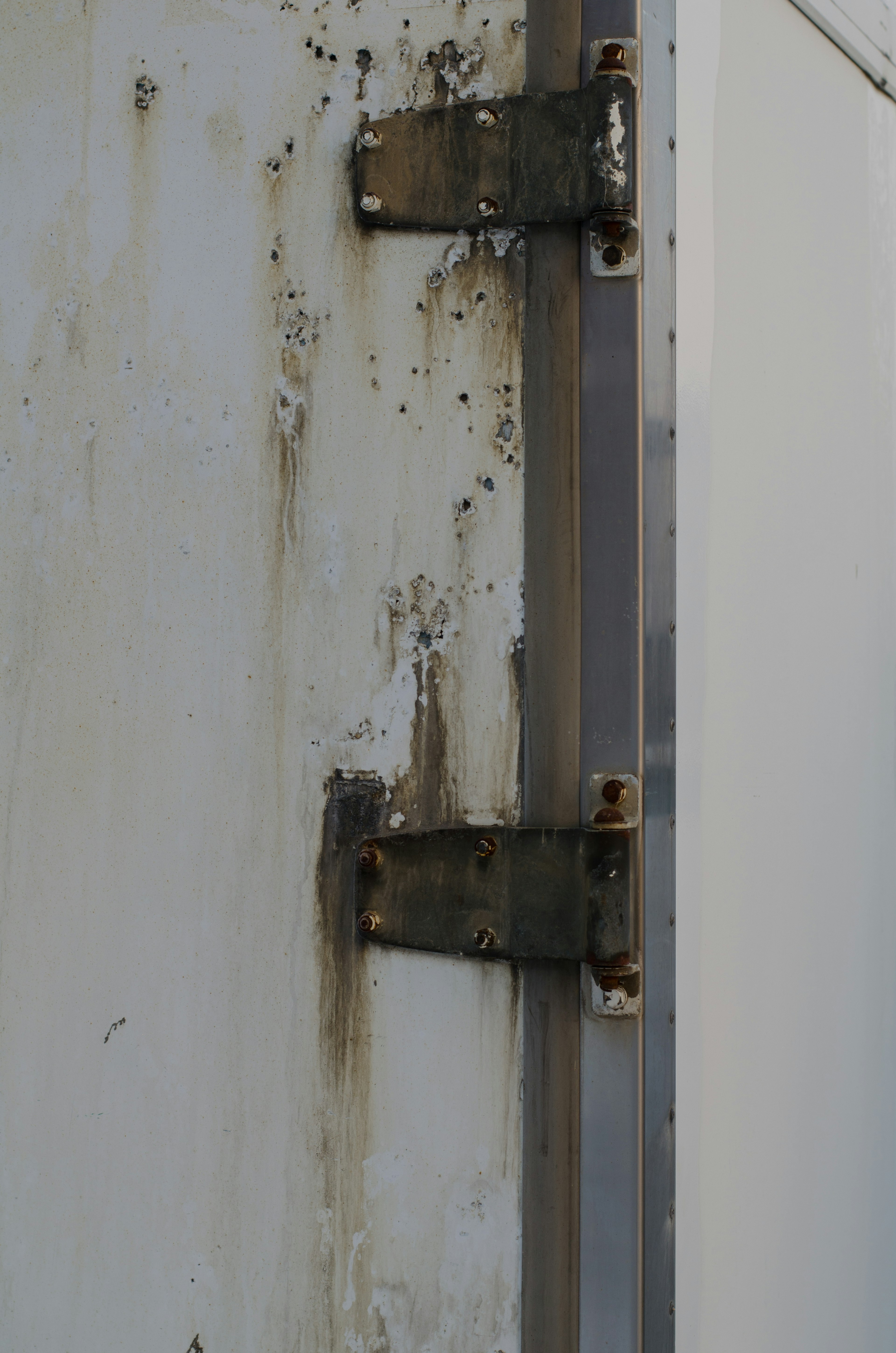 Image montrant des charnières en métal vieilles avec une surface murale sale