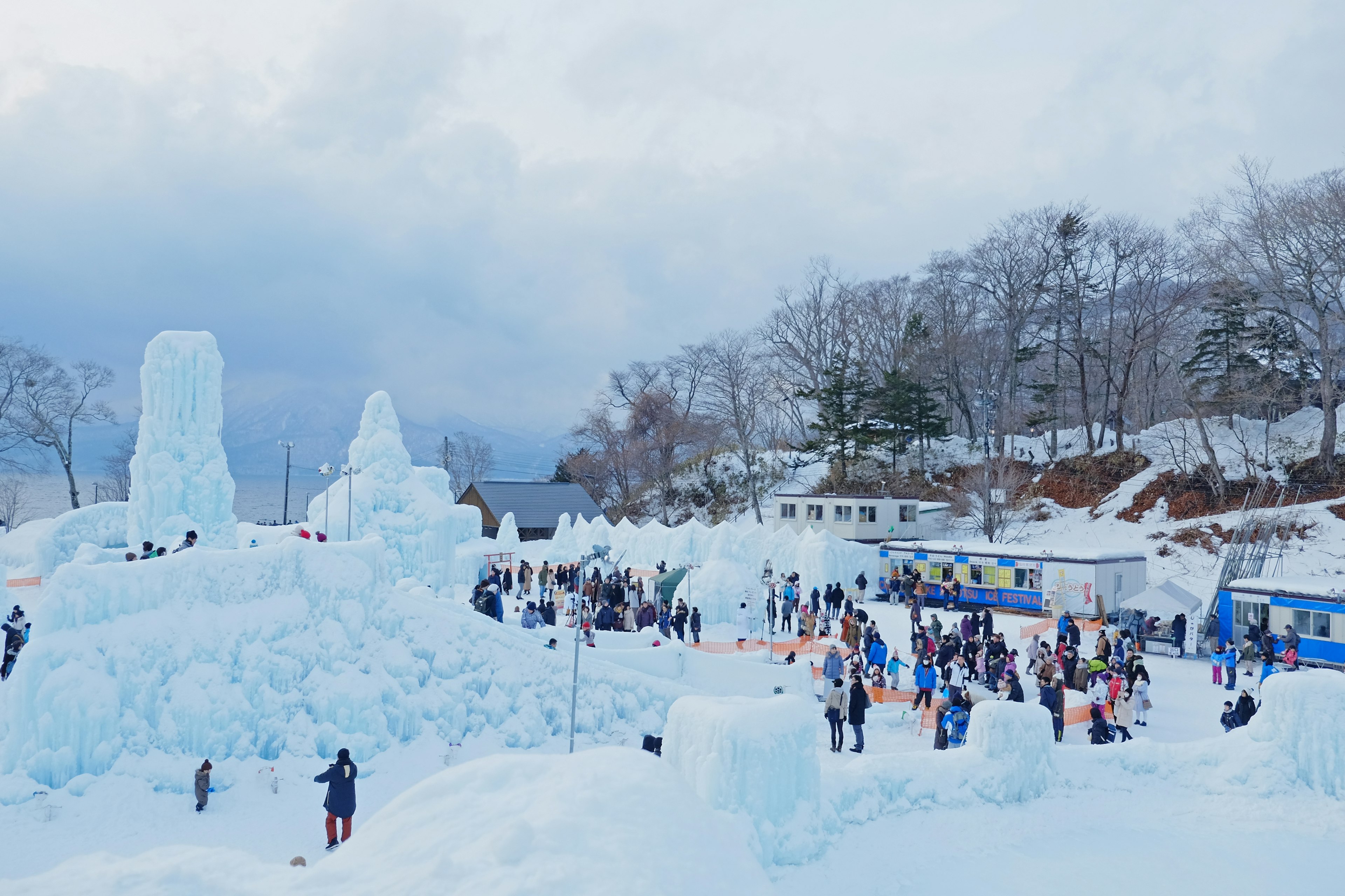 Scena di festival invernale con sculture di ghiaccio persone che si divertono nel paesaggio innevato