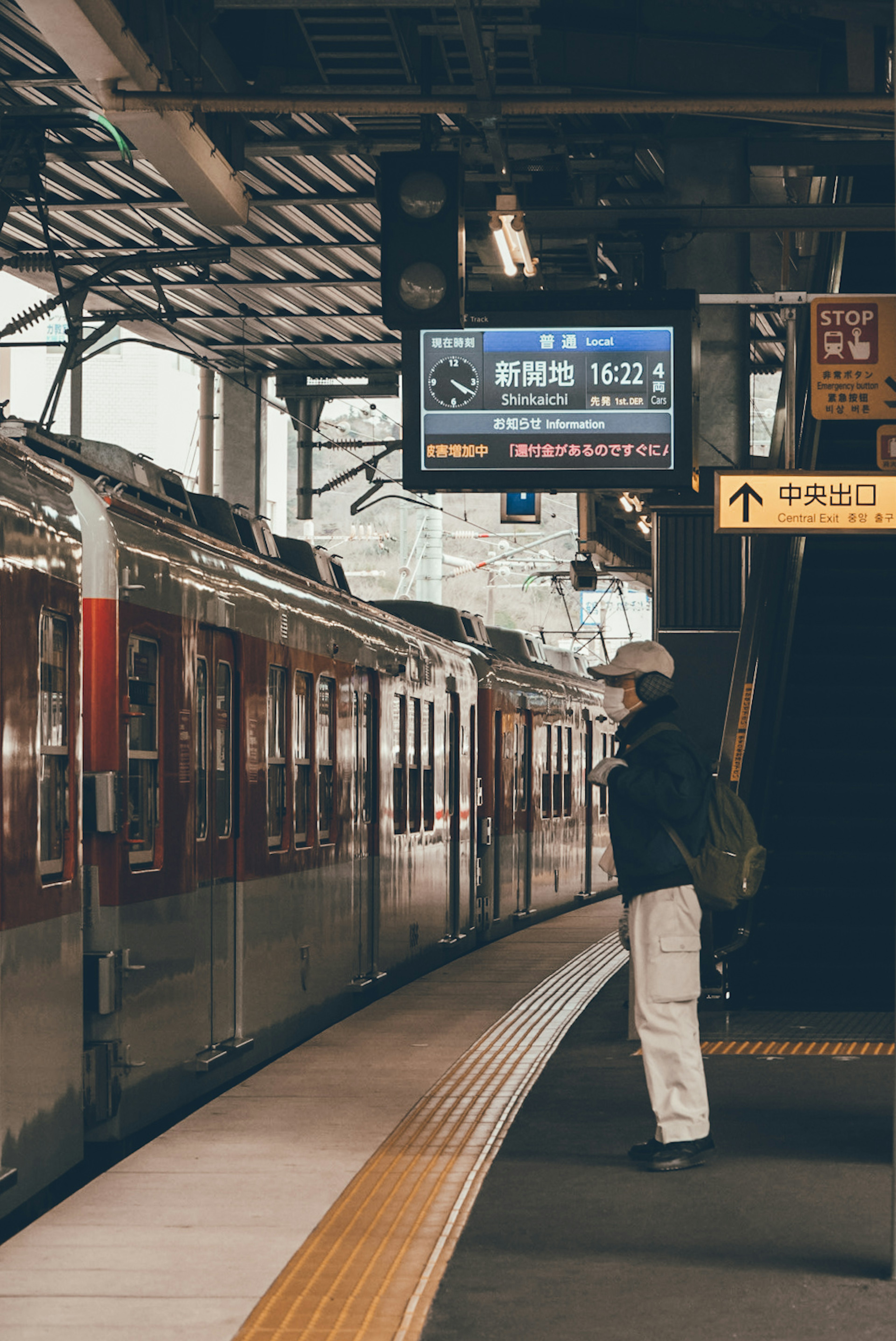 Person waiting for a train at a station with a display board