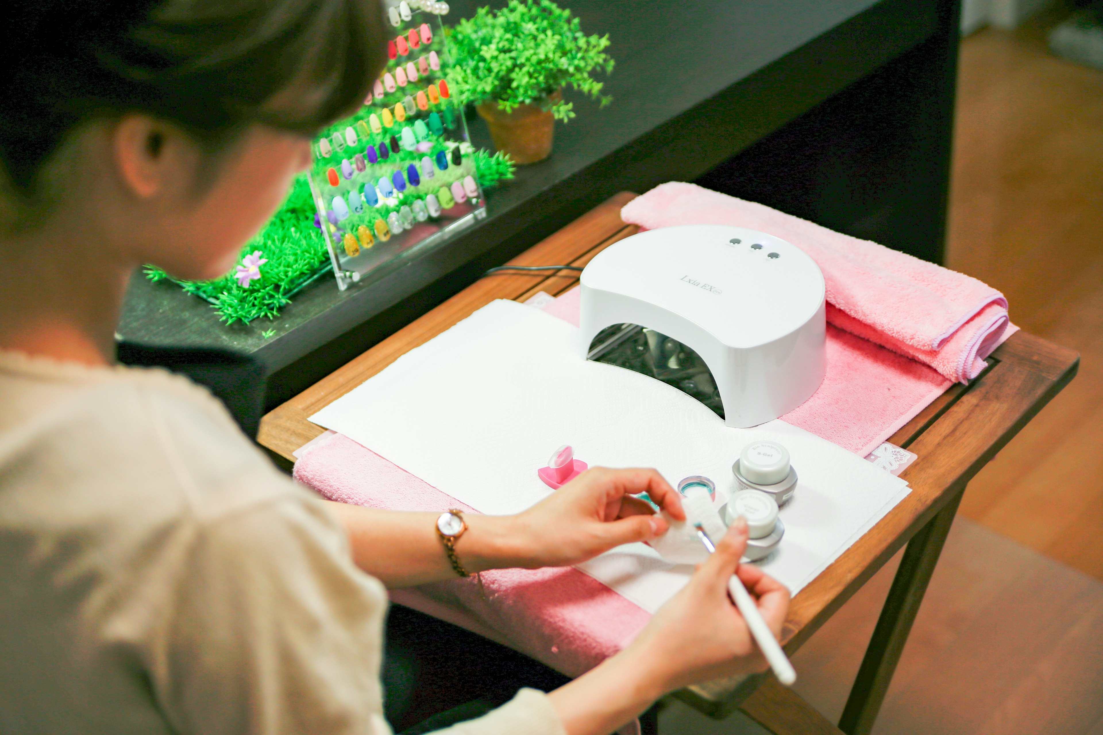 Una mujer haciendo arte en las uñas con un secador de uñas en un salón de belleza