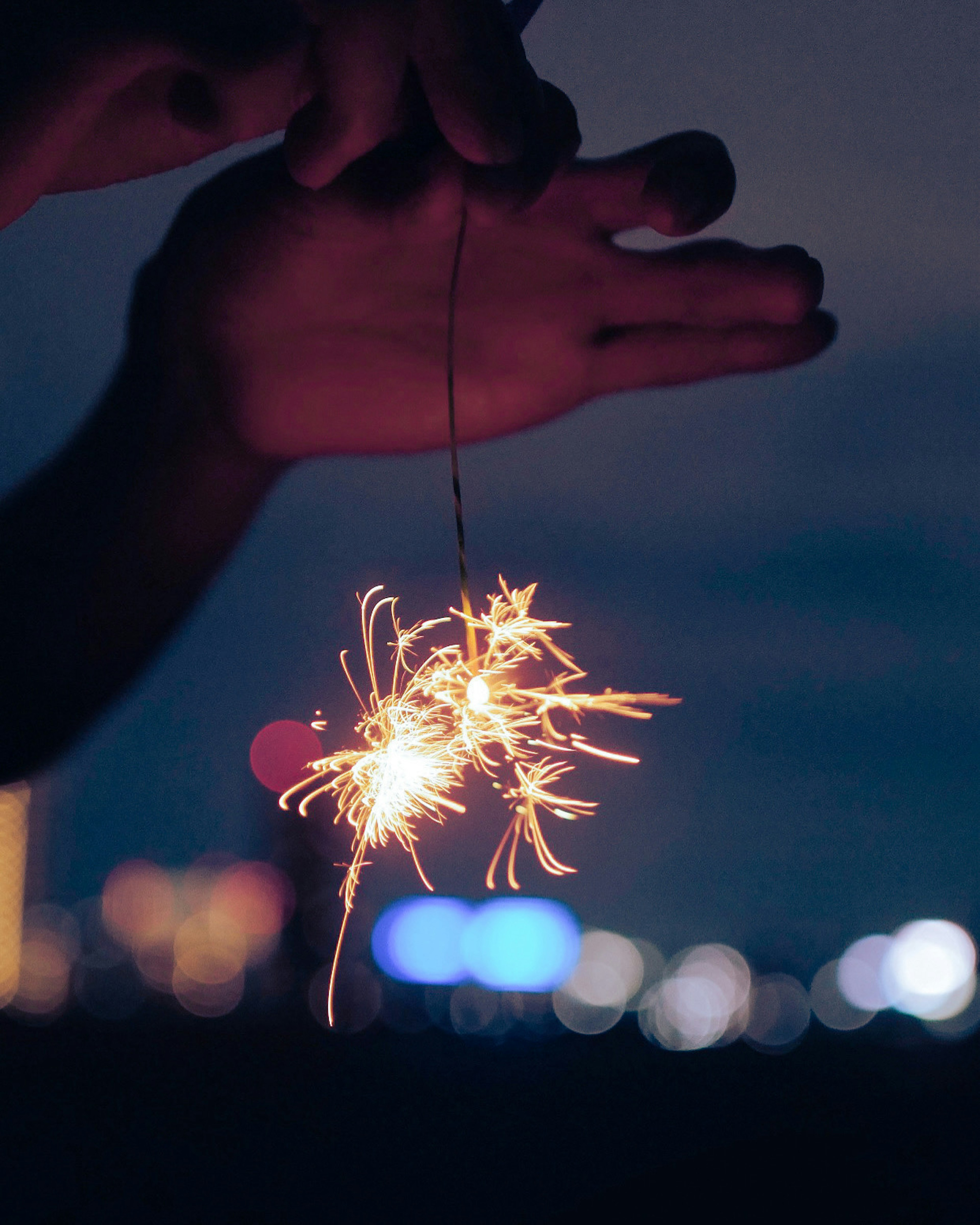 Mani che tengono un fuoco d'artificio scintillante di notte