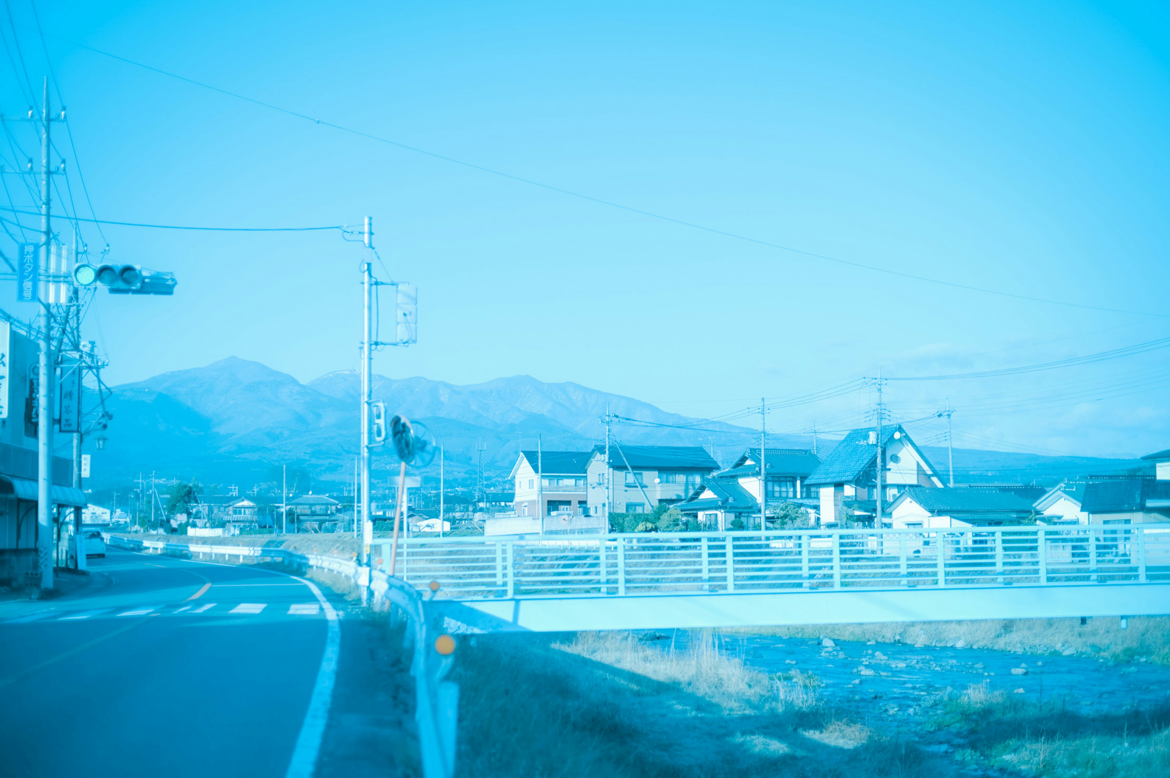 Rural landscape with blue tones featuring mountains and houses