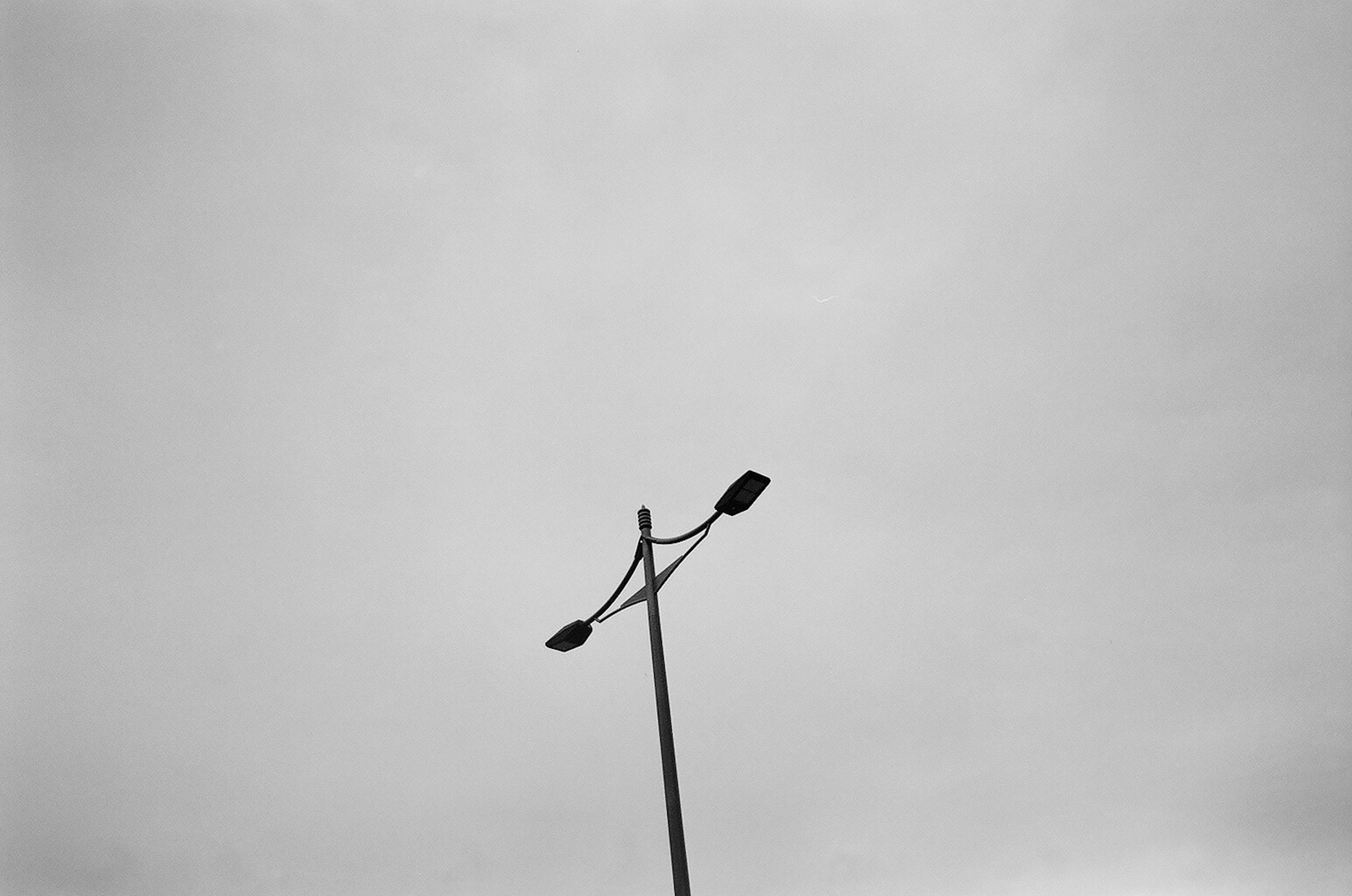 Polo de farola con lámparas contra un cielo gris