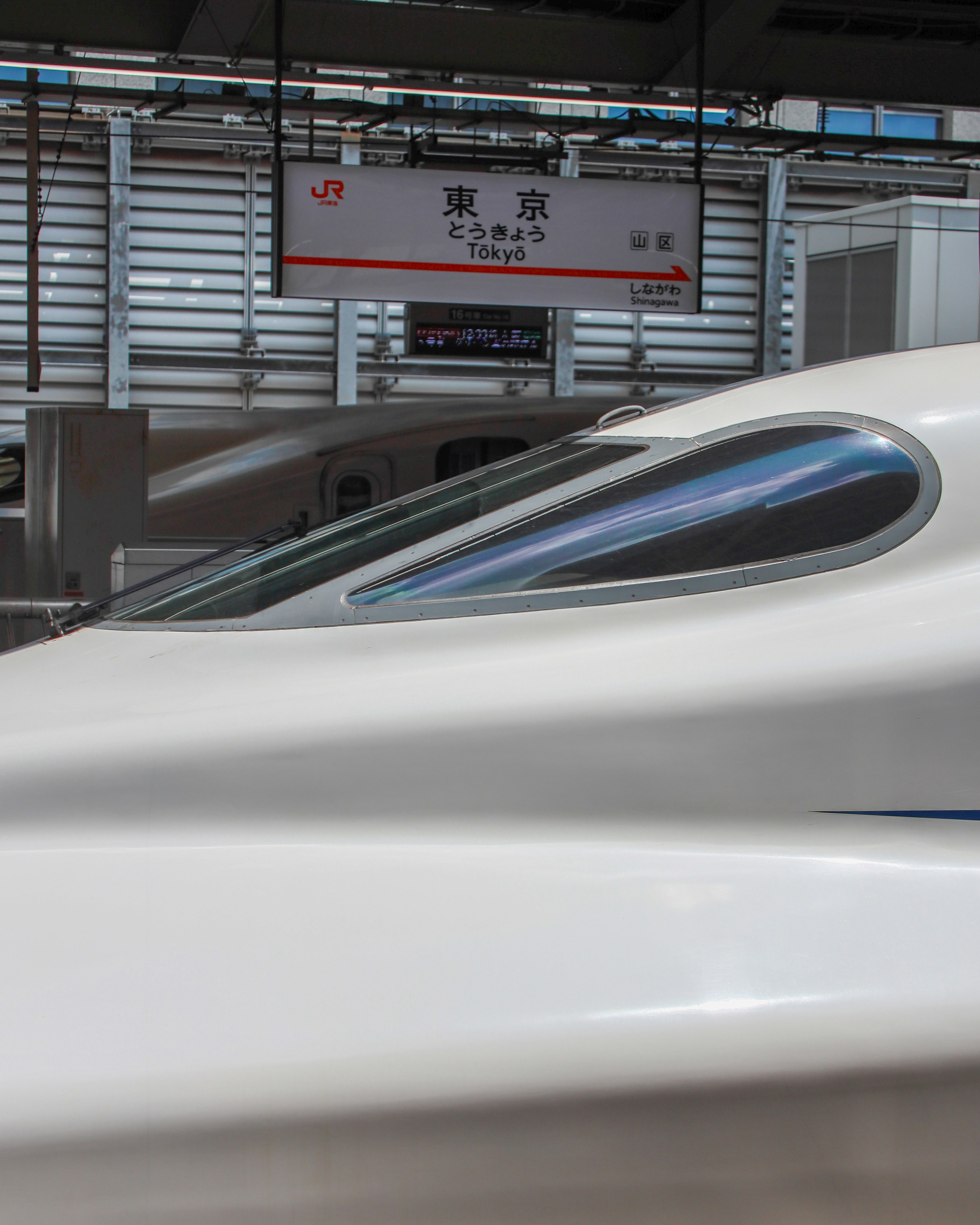 Immagine che mostra il lato di uno Shinkansen e il segnale della stazione di Tokyo