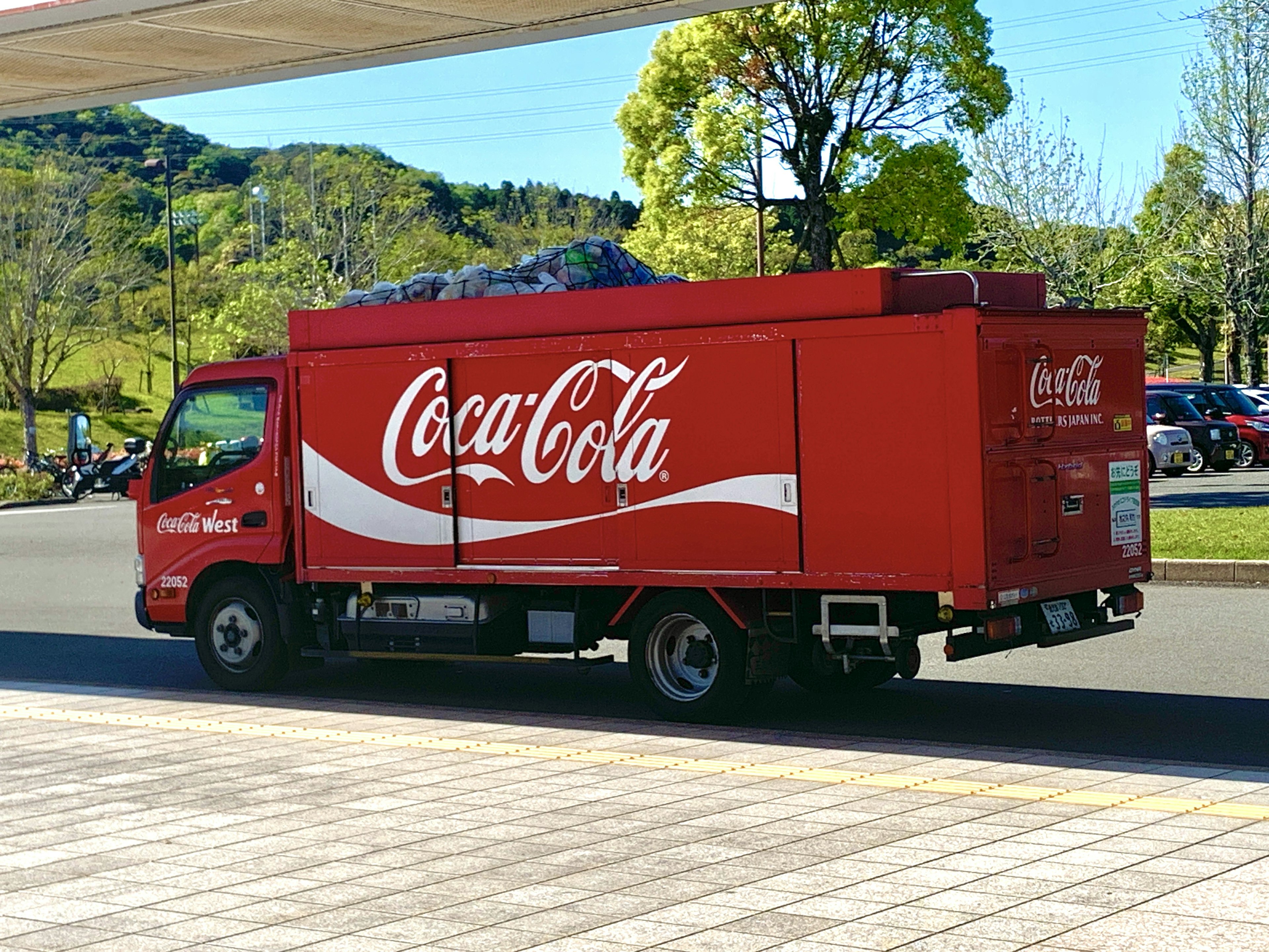 Red Coca-Cola truck driving through a green park