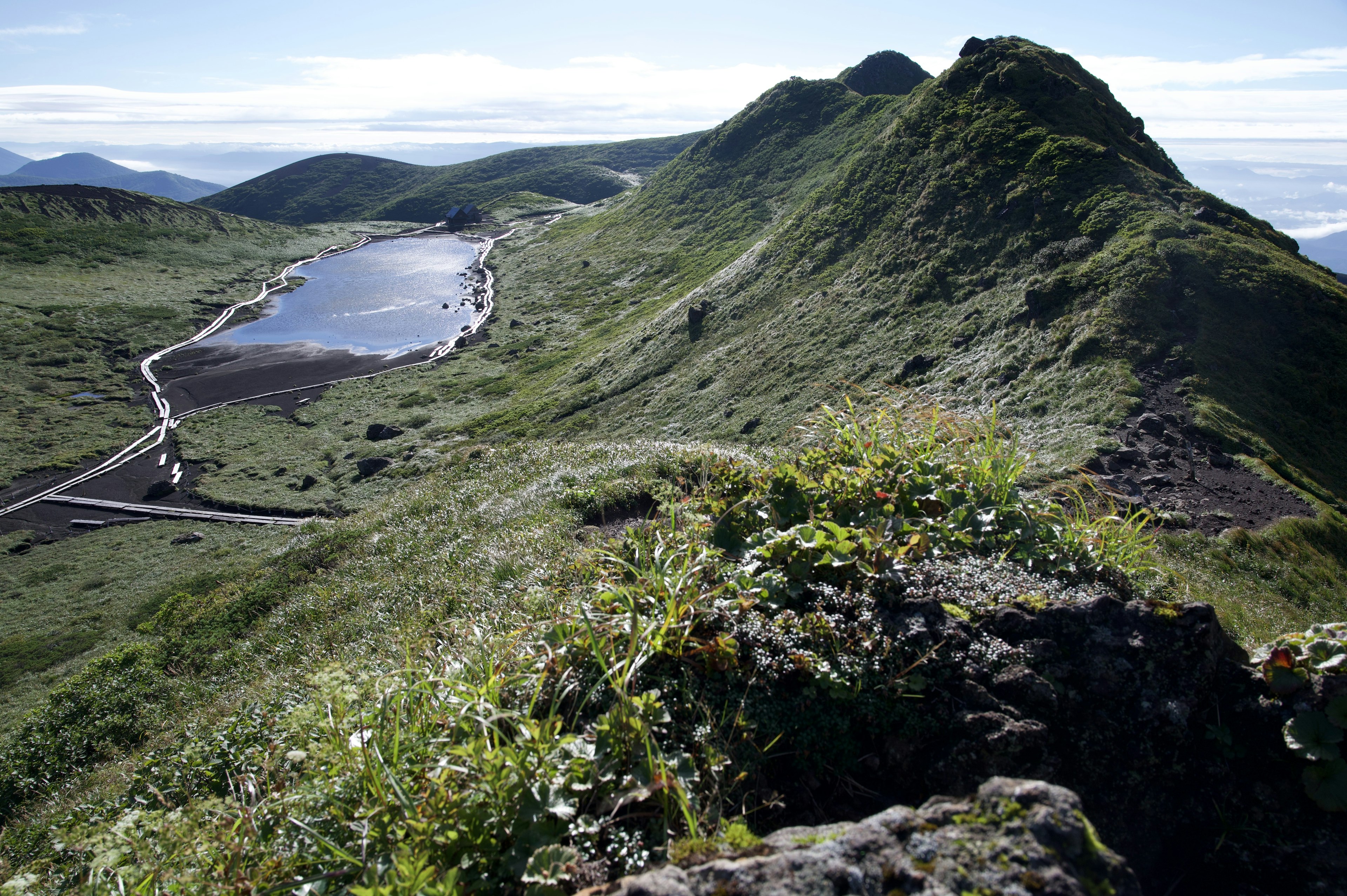 Lush green hills with a tranquil pond in the foreground