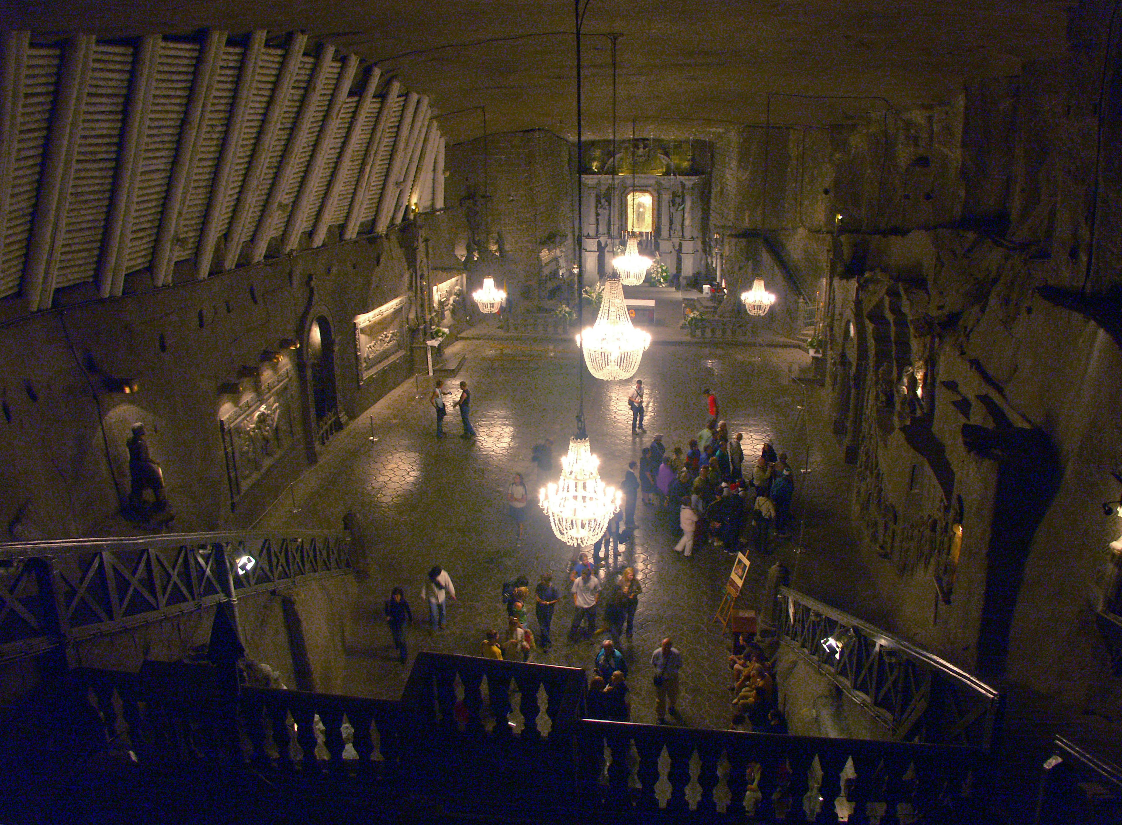 Blick auf das Innere einer unterirdischen Kathedrale mit großen Kronleuchtern und versammelten Menschen