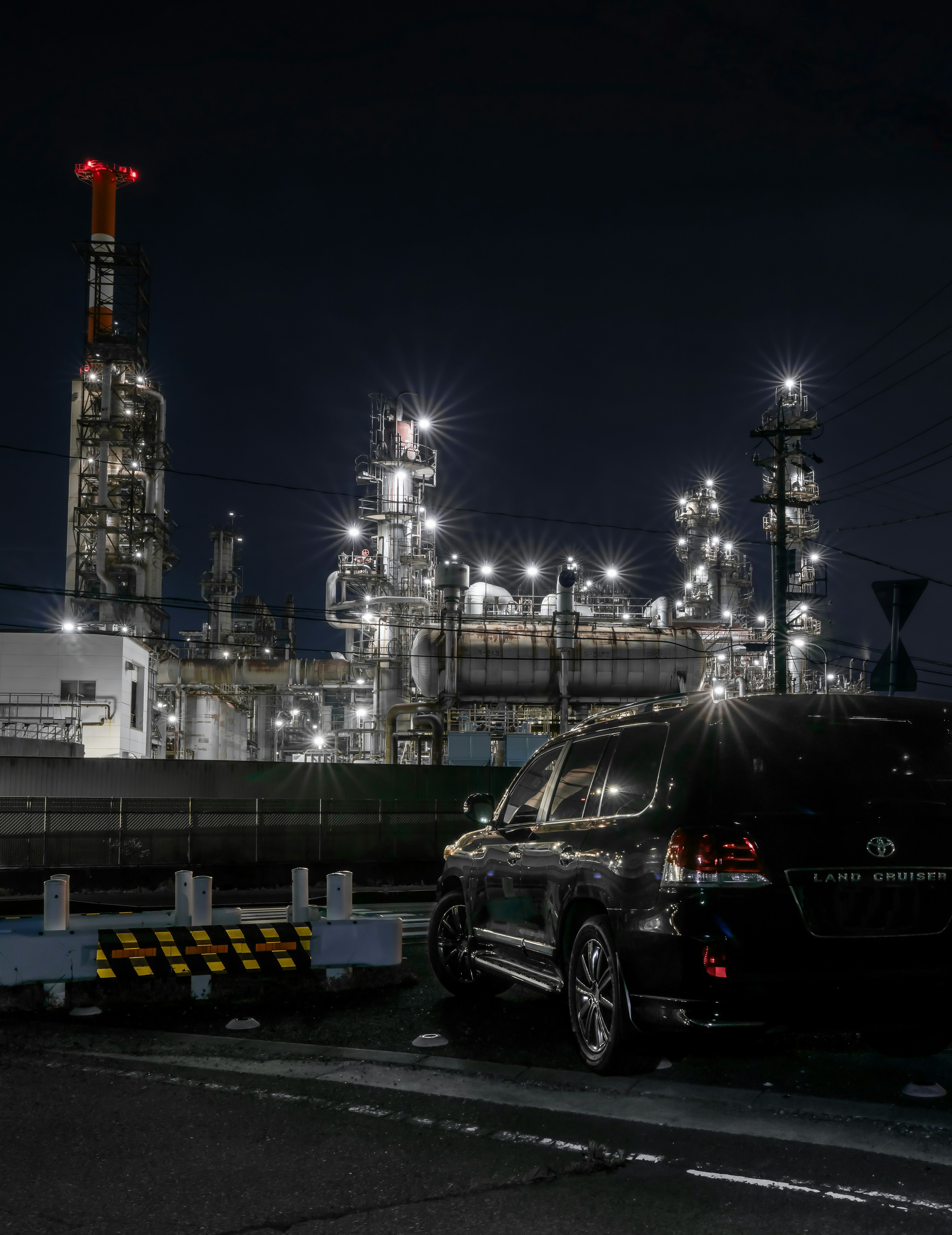 Vista nocturna de una planta industrial con un SUV negro