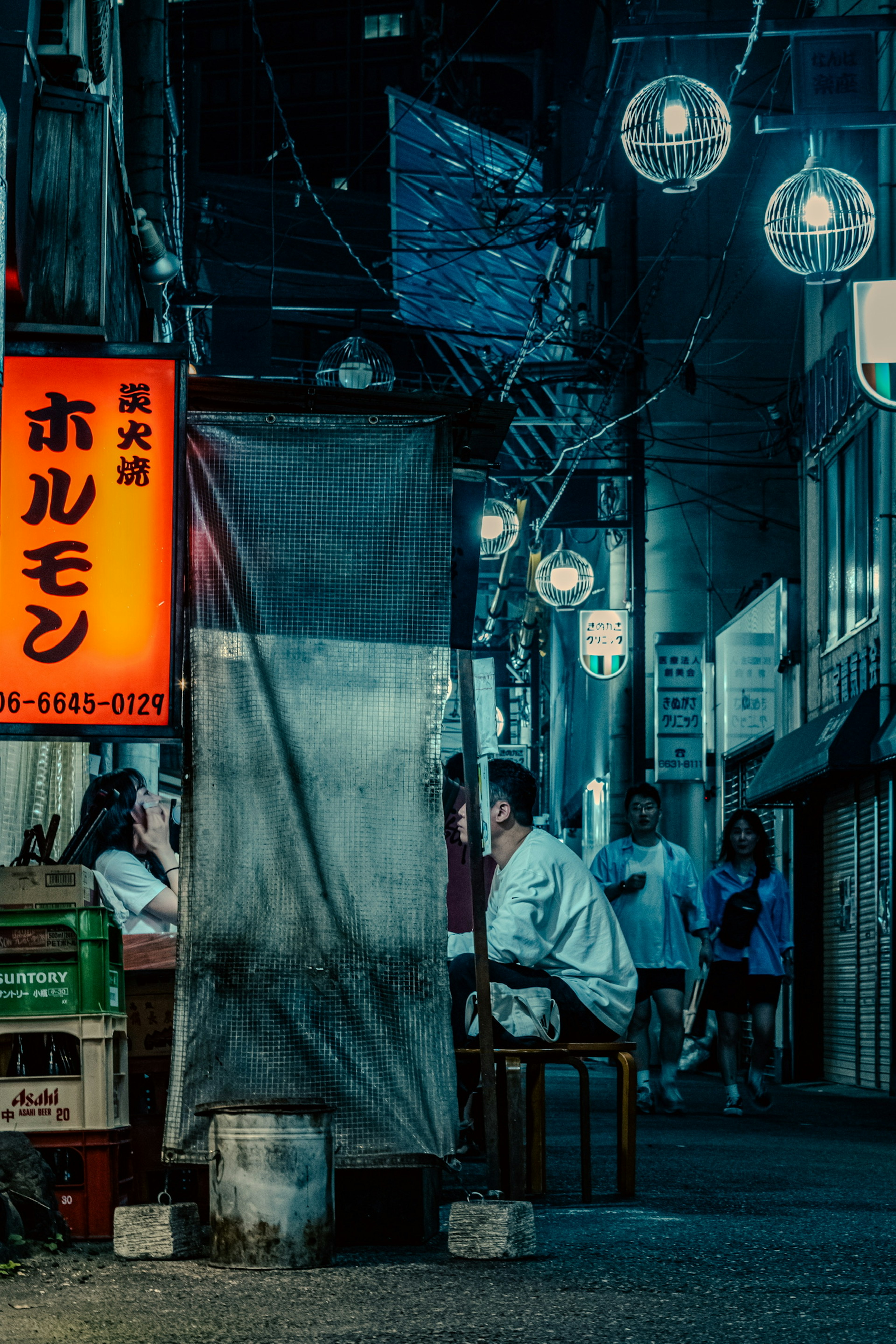 薄暗い小道に並ぶランプと飲食店の看板が印象的な夜の風景