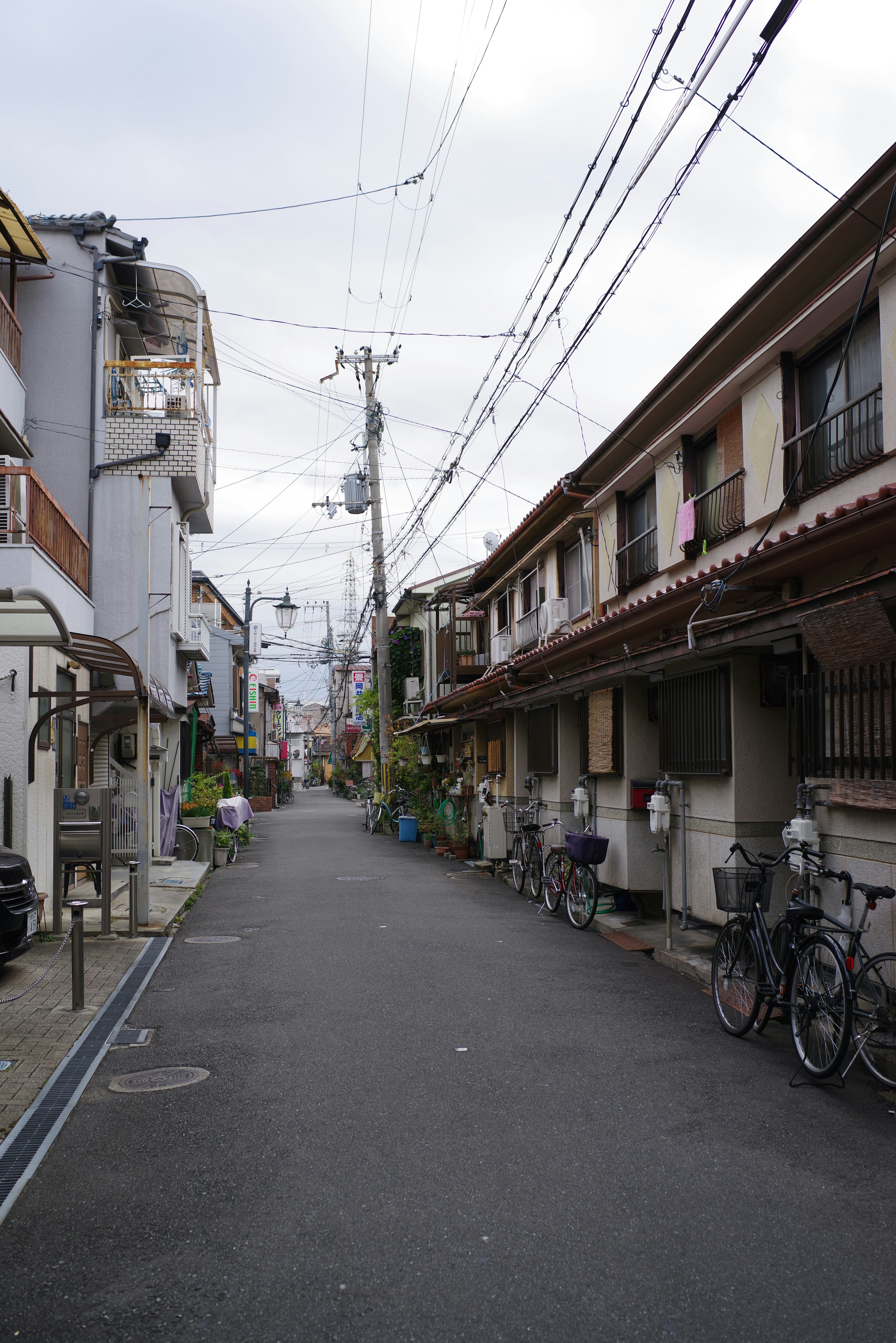 ถนนที่อยู่อาศัยเงียบสงบในญี่ปุ่นมีจักรยานและสายไฟ