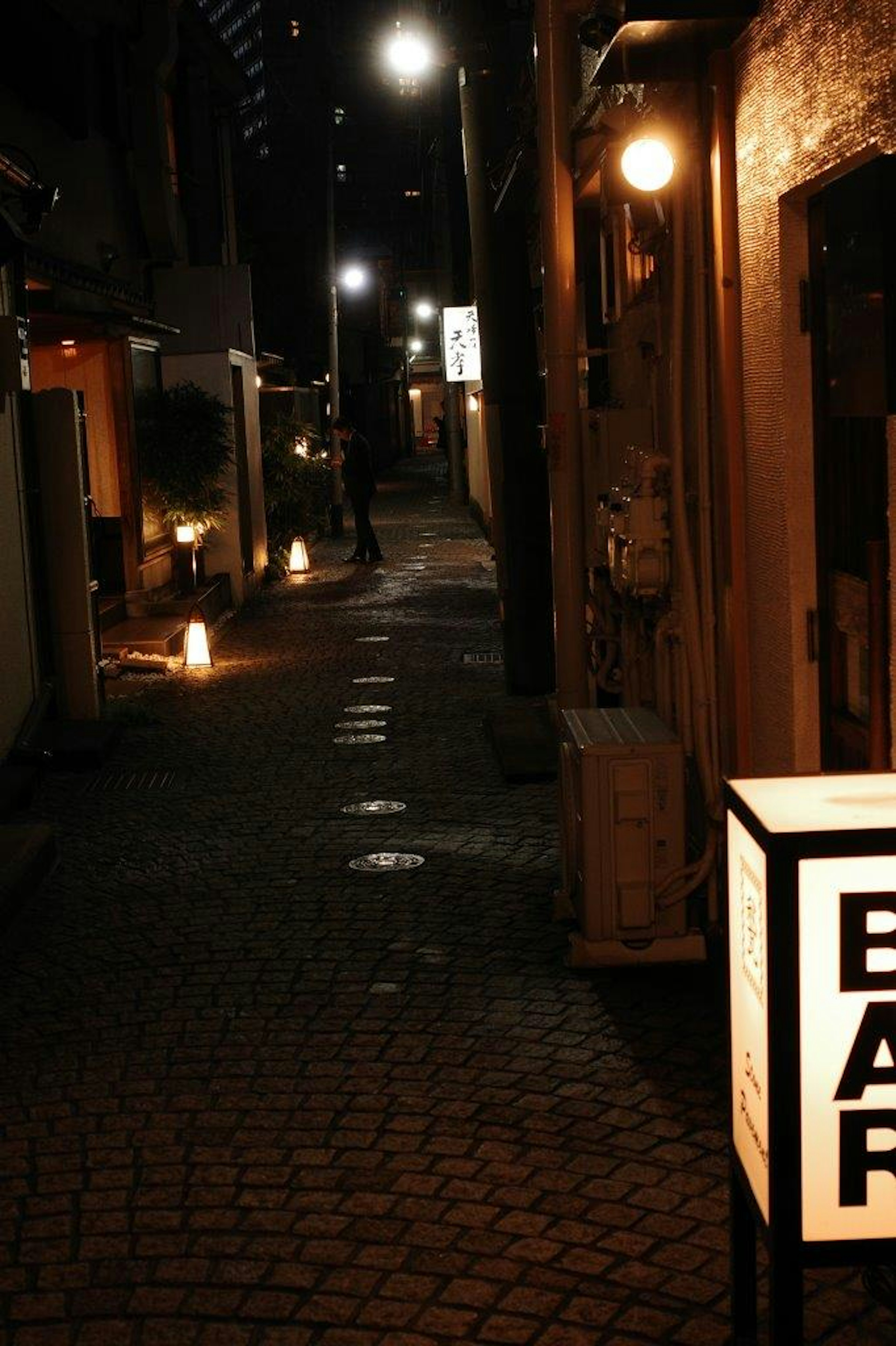 Gang sempit di malam hari dengan pencahayaan lembut dan papan bar