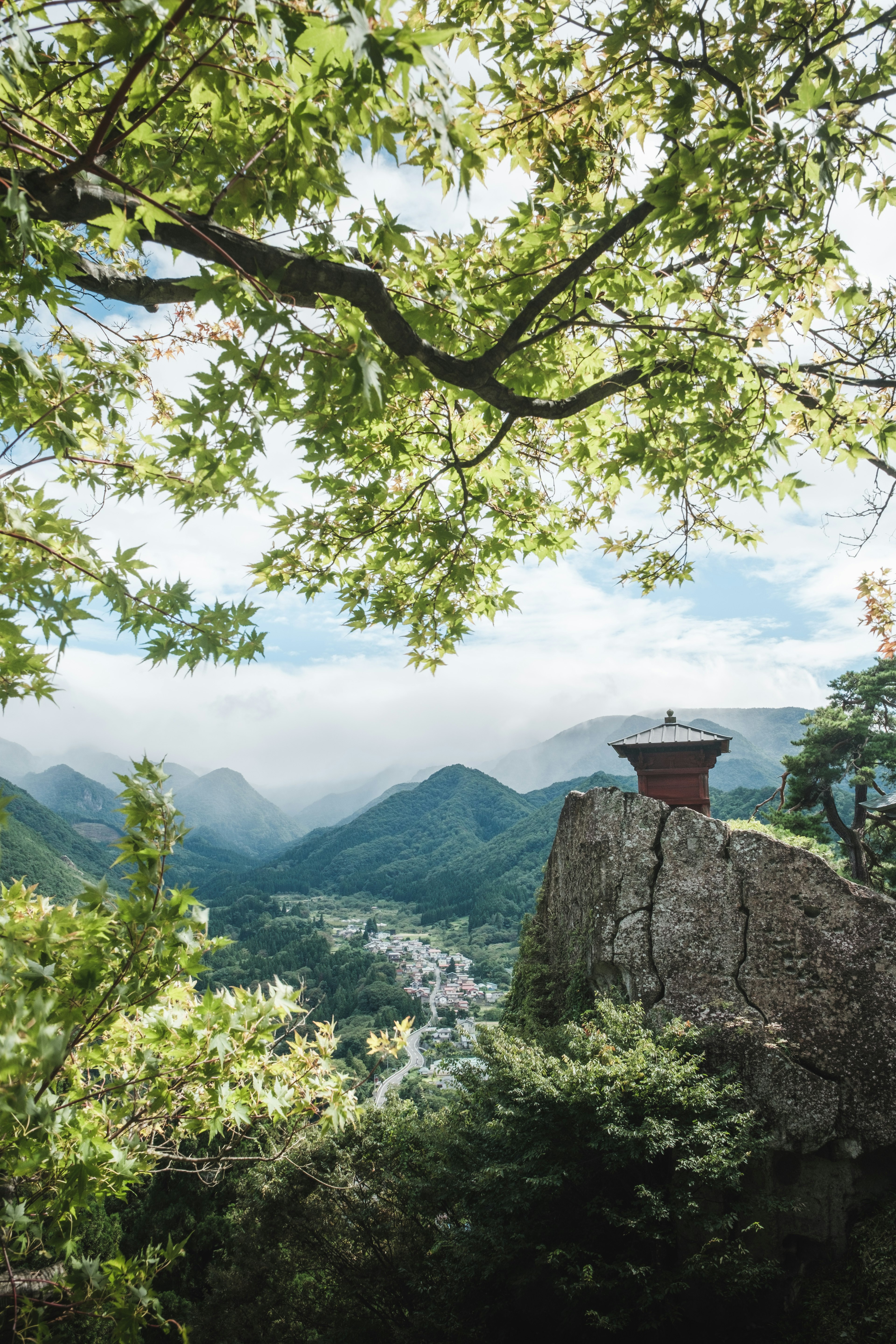 山の上にある小さな建物と緑の木々の間から見える美しい風景