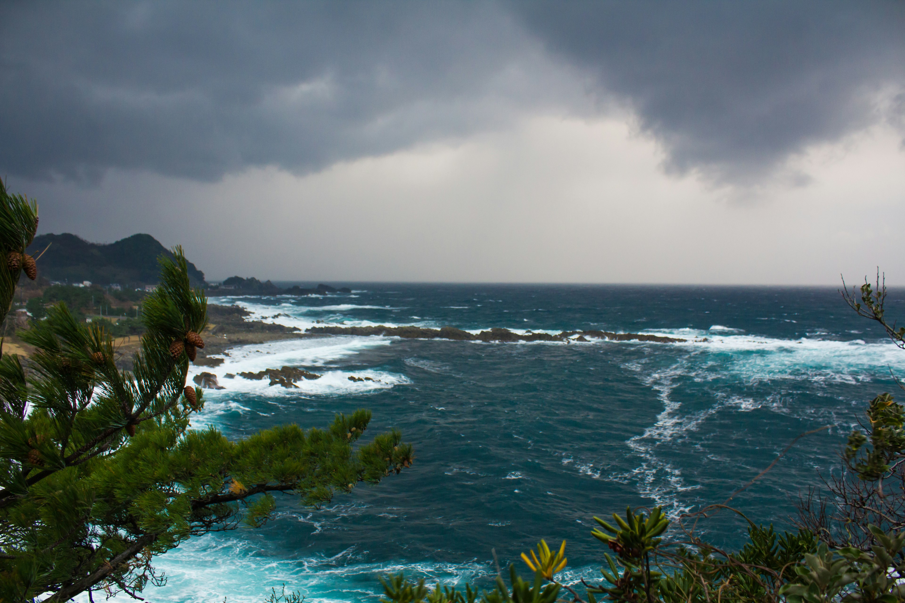 Paesaggio costiero con nuvole scure mare blu e onde bianche