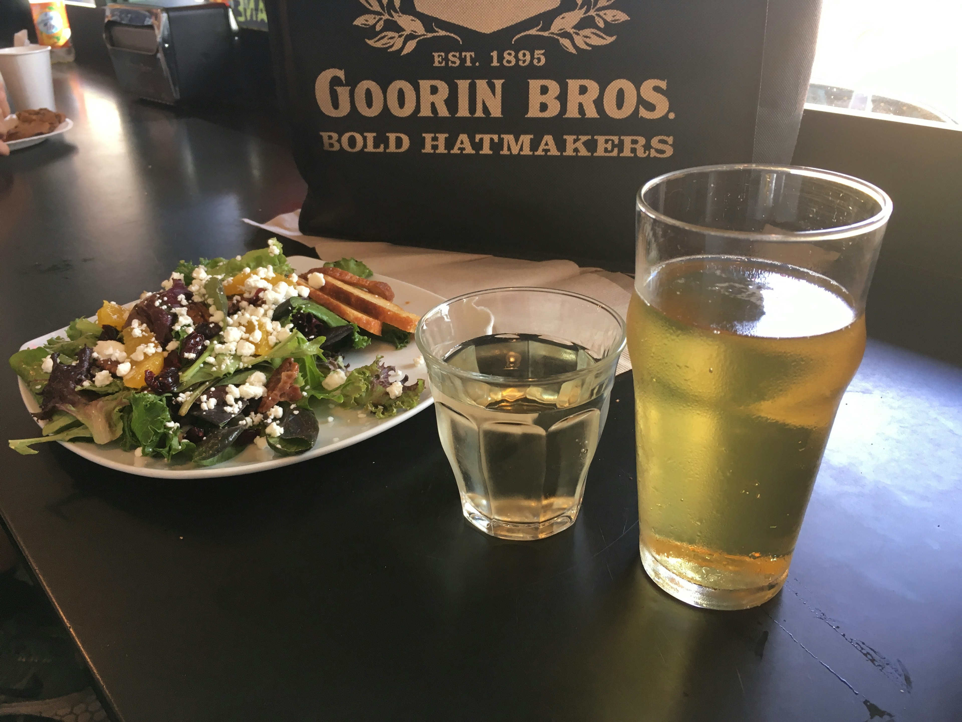 Table with a salad and drinks including a glass of beer and a shot