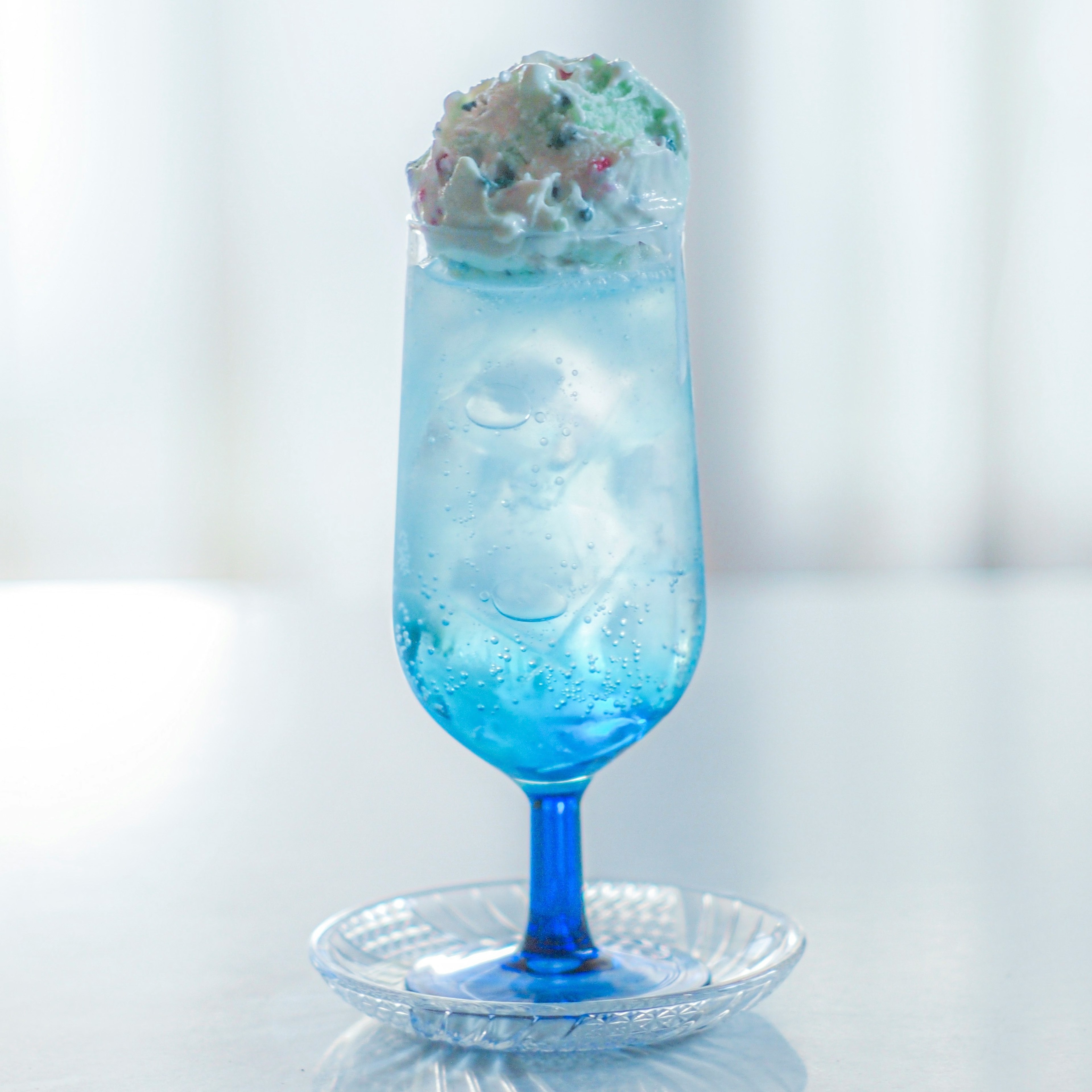 A blue cocktail glass with whipped cream and colorful toppings on a drink