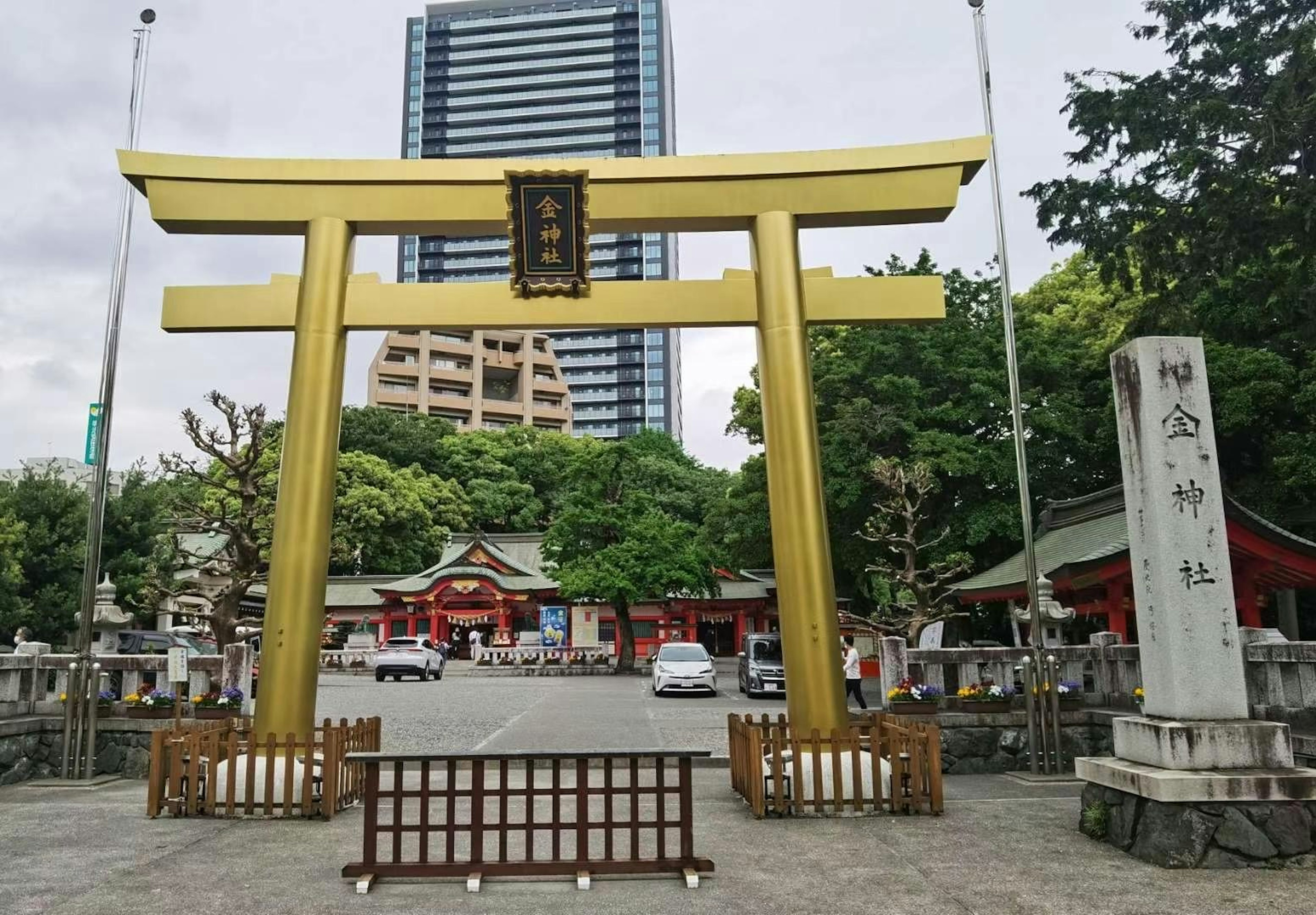 Portale torii dorato con un santuario sullo sfondo edifici moderni visibili