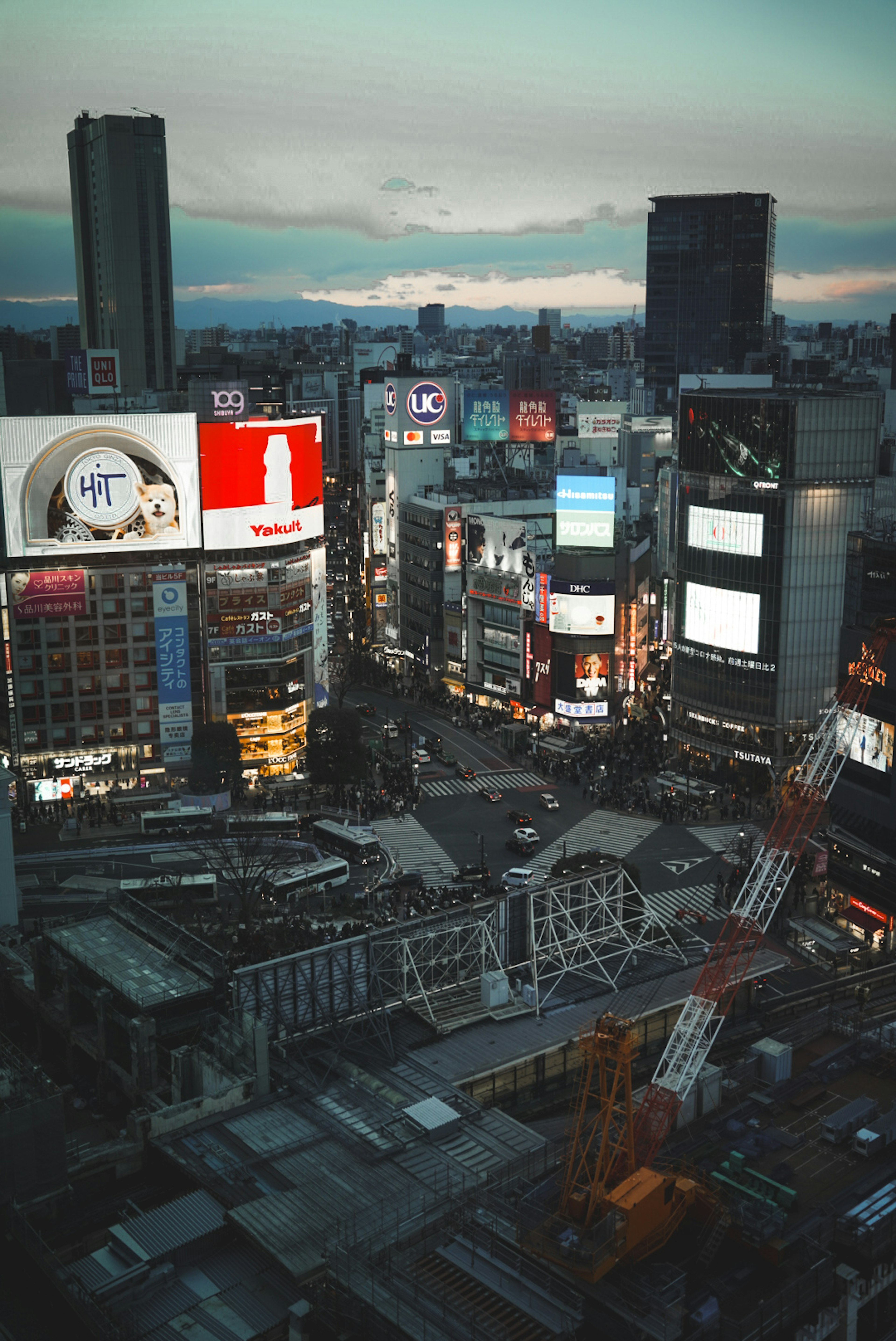 Shibuya Crossing at dusk with skyscrapers and neon signs