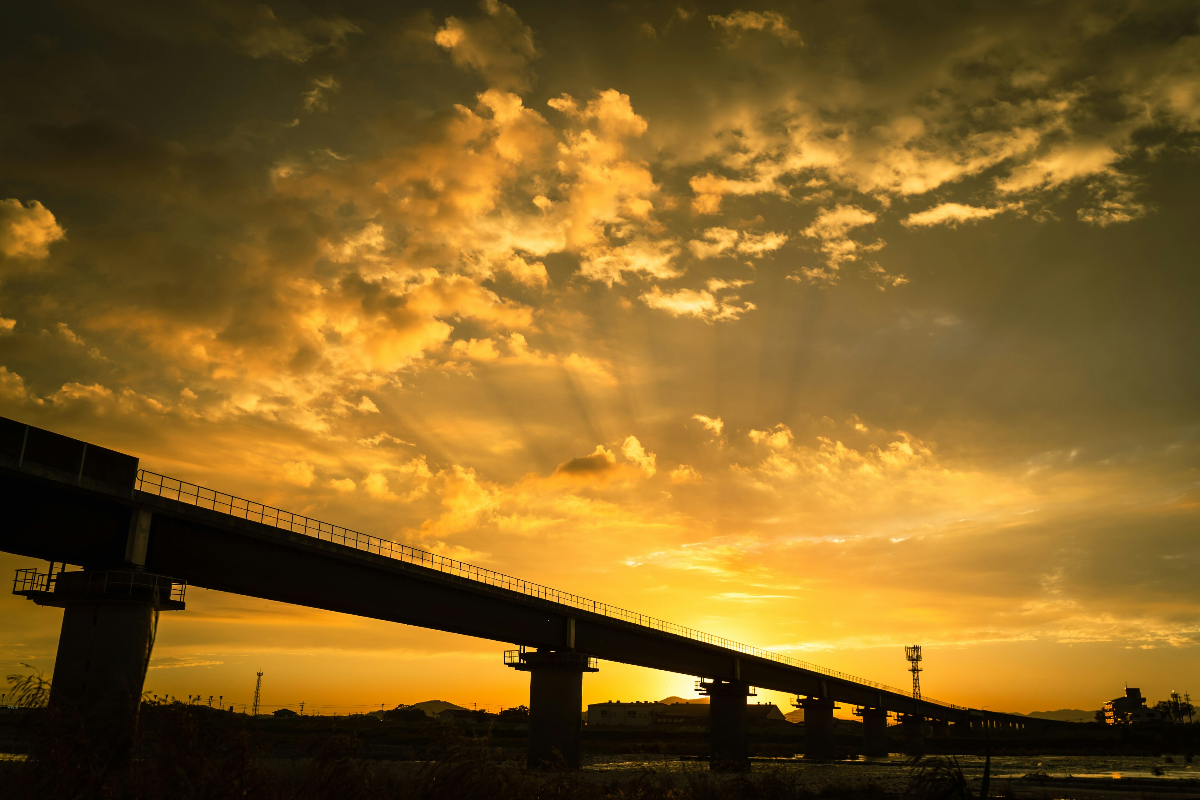 夕日の下に広がる橋のシルエットと色彩豊かな空