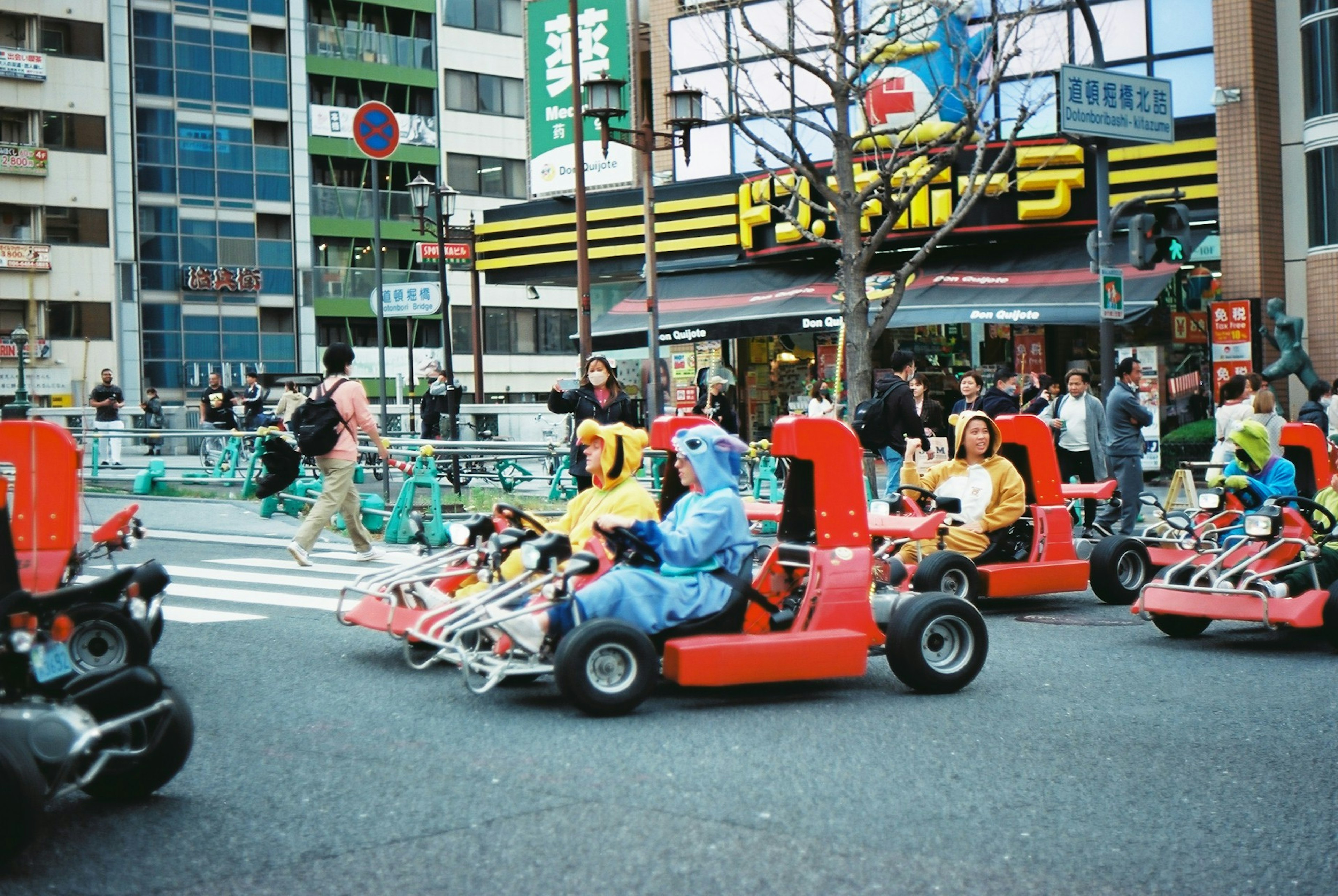 Gruppe von Menschen, die in bunten Kostümen auf einer Straße in Tokio Go-Karts fahren