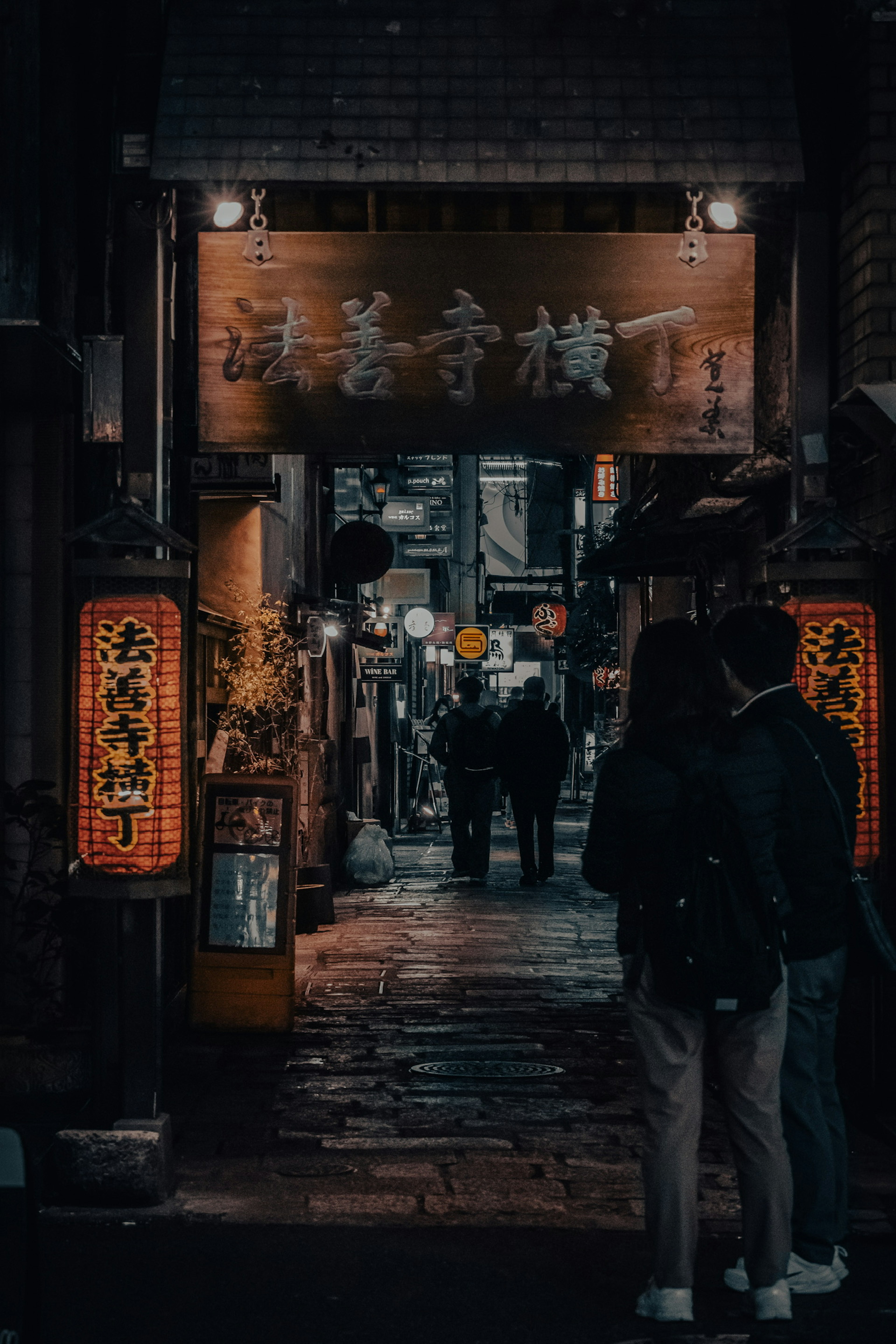 Entrada de un izakaya en un callejón oscuro con faroles