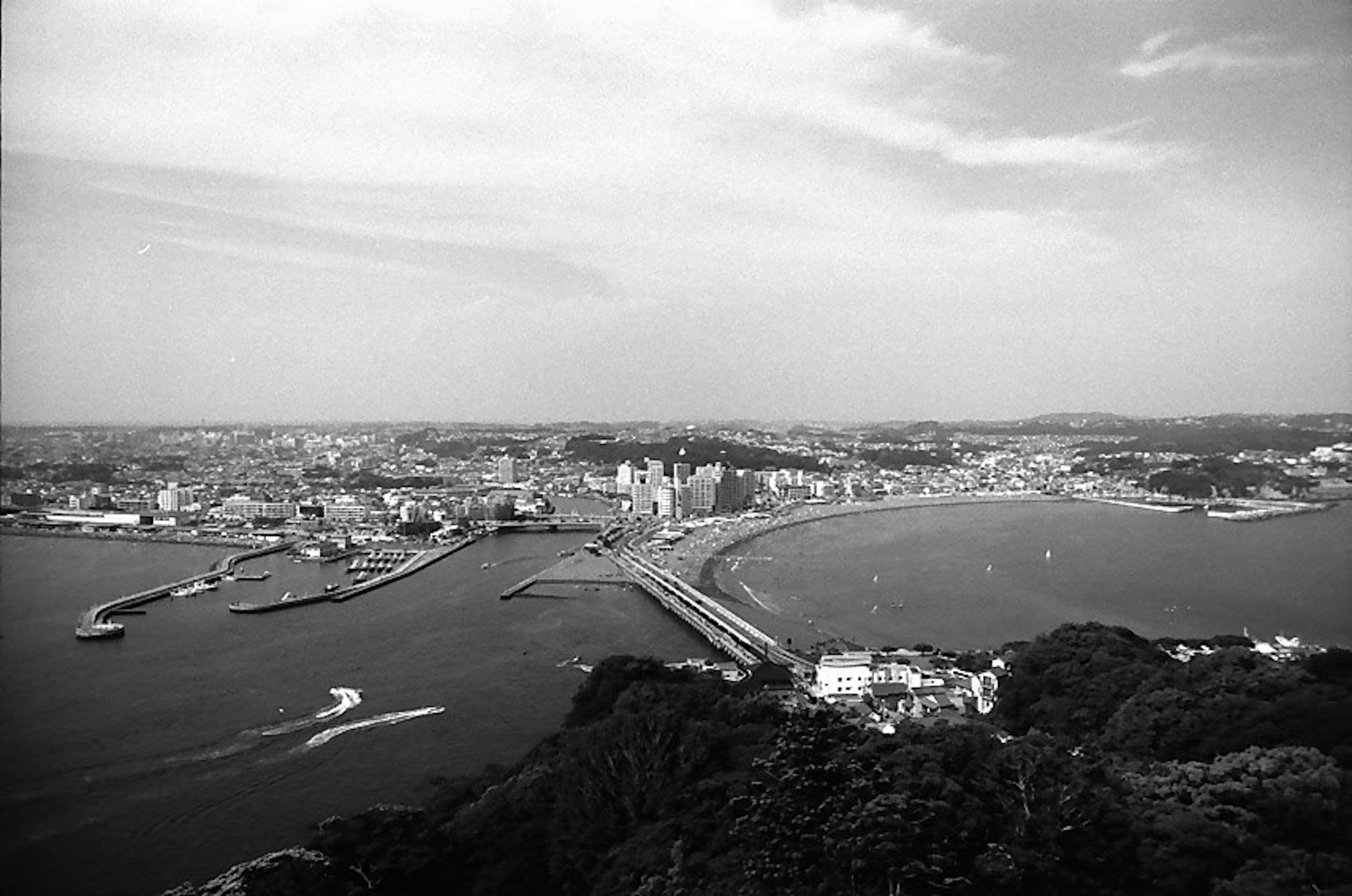 Vue en noir et blanc d'une ville côtière avec un pont et des bateaux