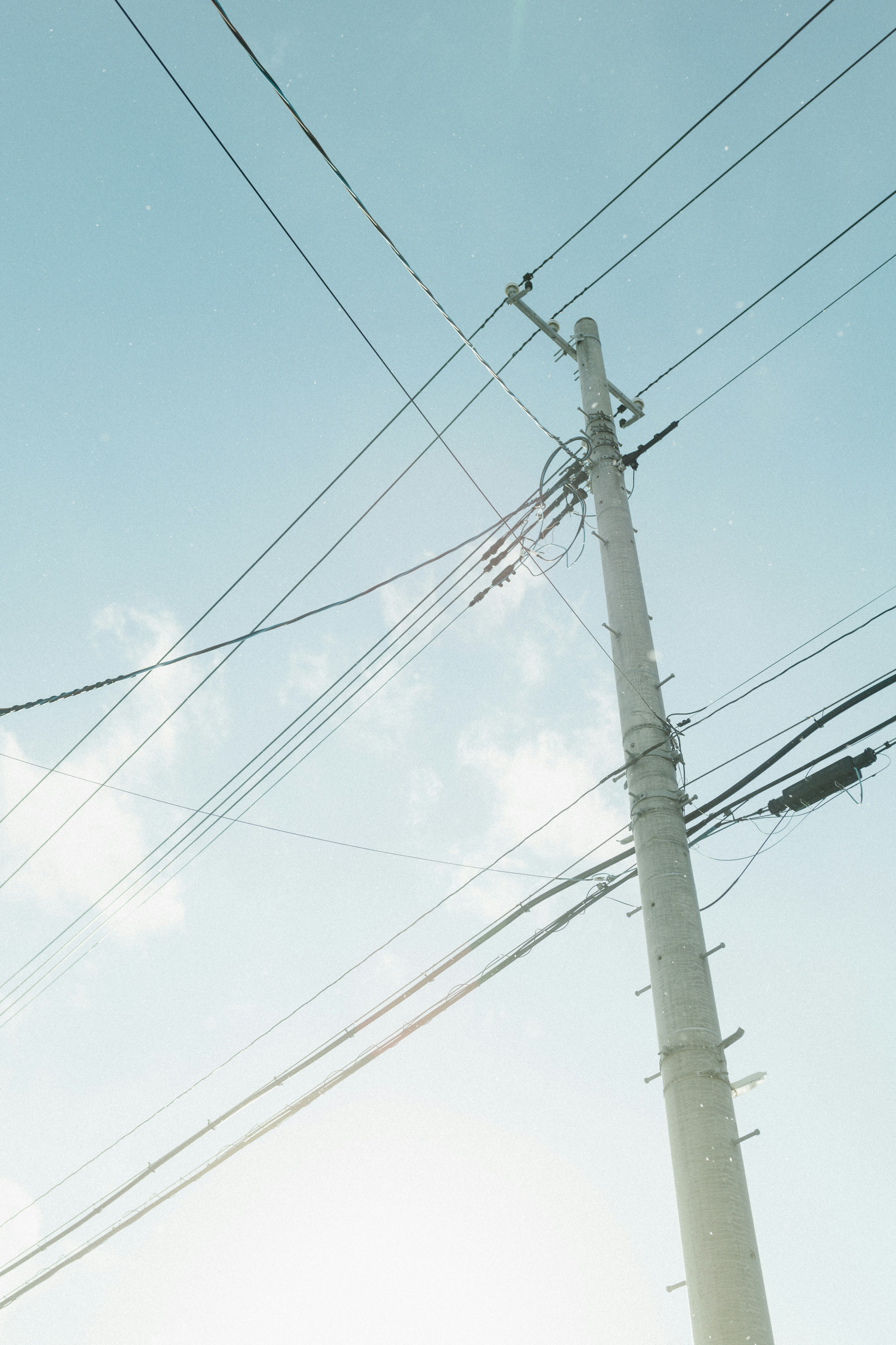 Un paysage avec un poteau électrique sous un ciel bleu et des lignes électriques croisées