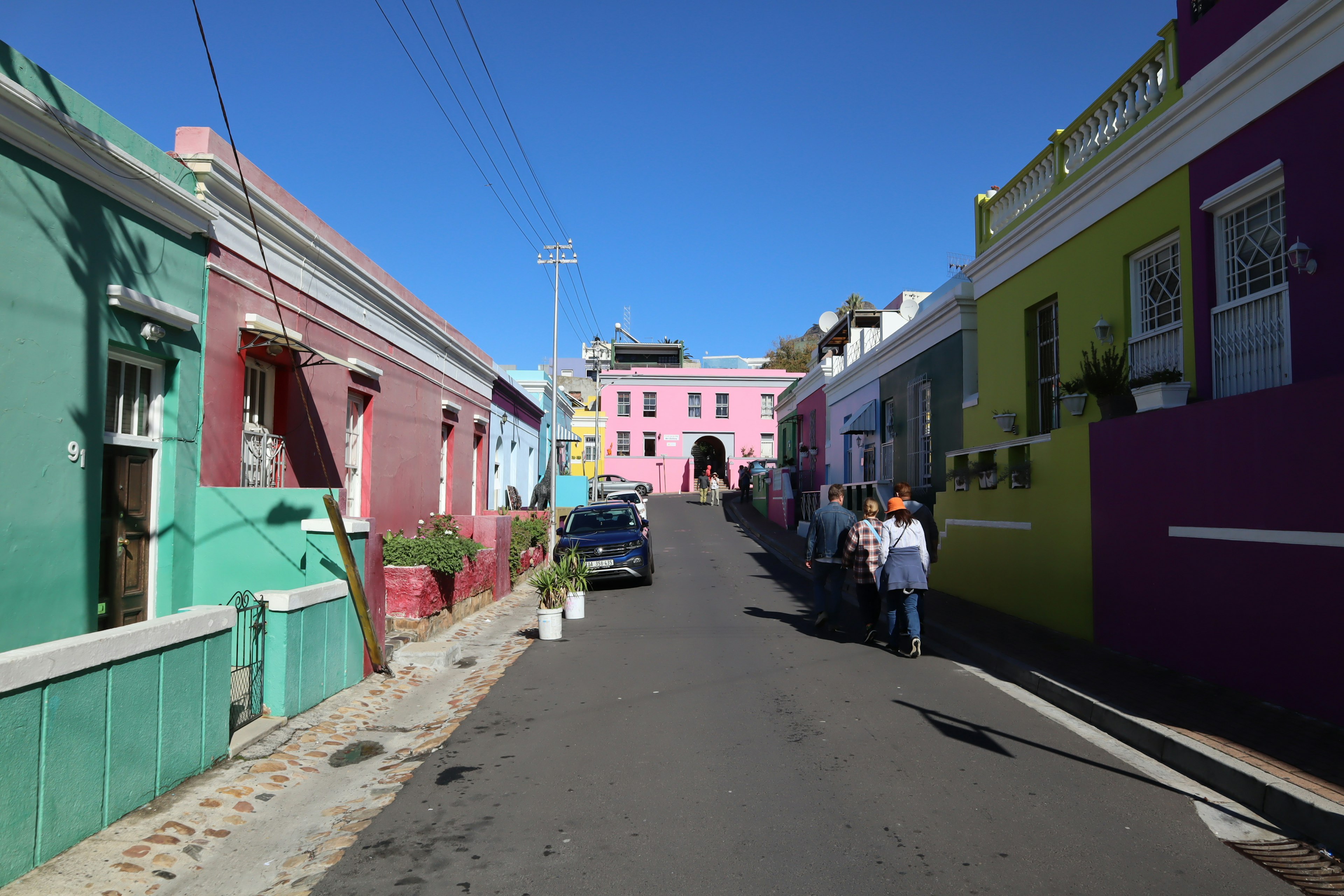 Colorful houses lining a street under a blue sky featuring green and pink buildings