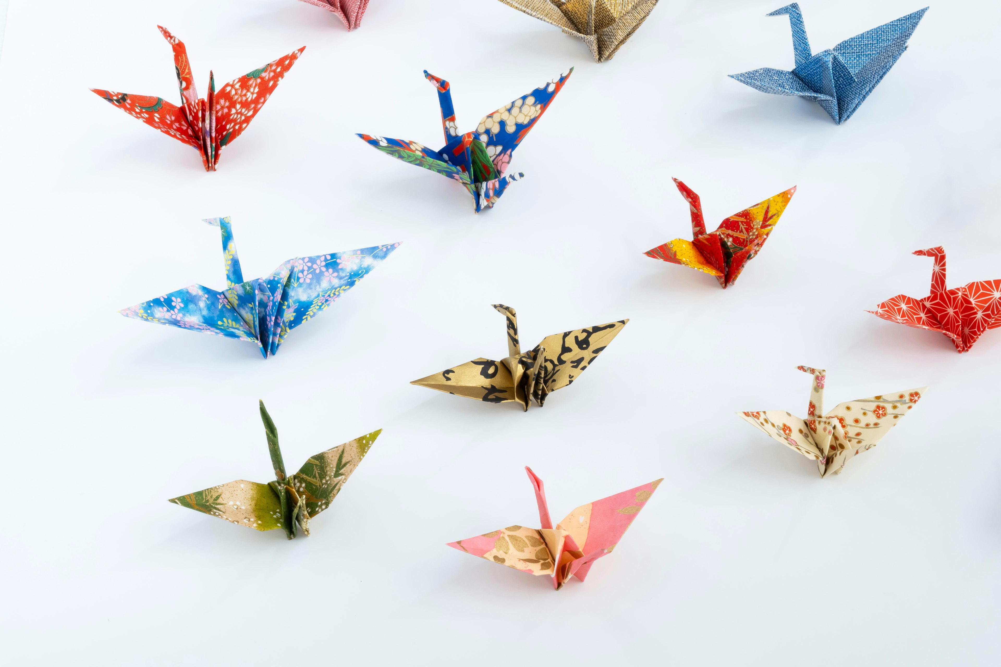 Des grues en origami colorées disposées sur un fond blanc