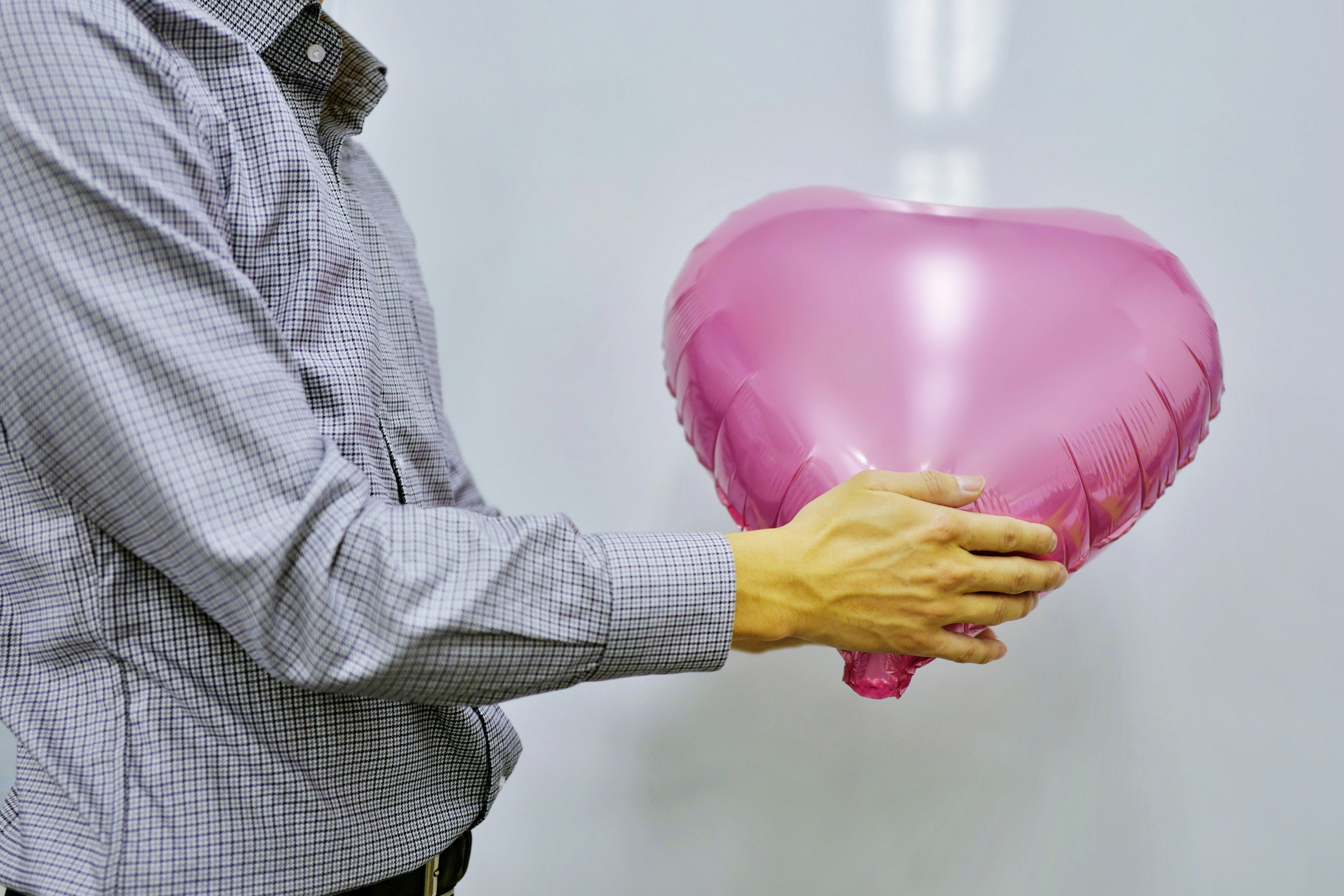 Un hombre sosteniendo un globo en forma de corazón rosa