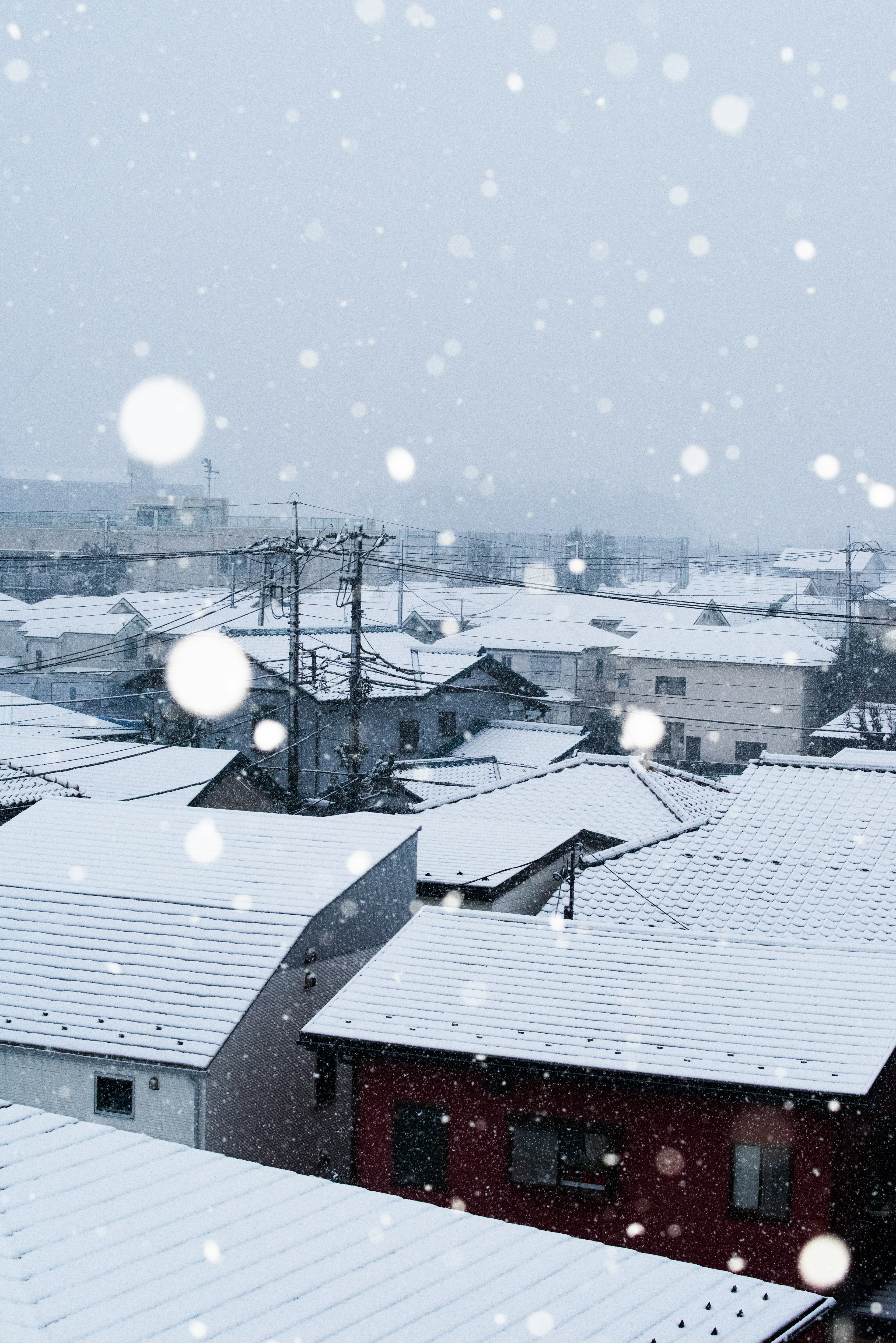 Winter scene of a snowy town rooftops covered in snow with falling snowflakes