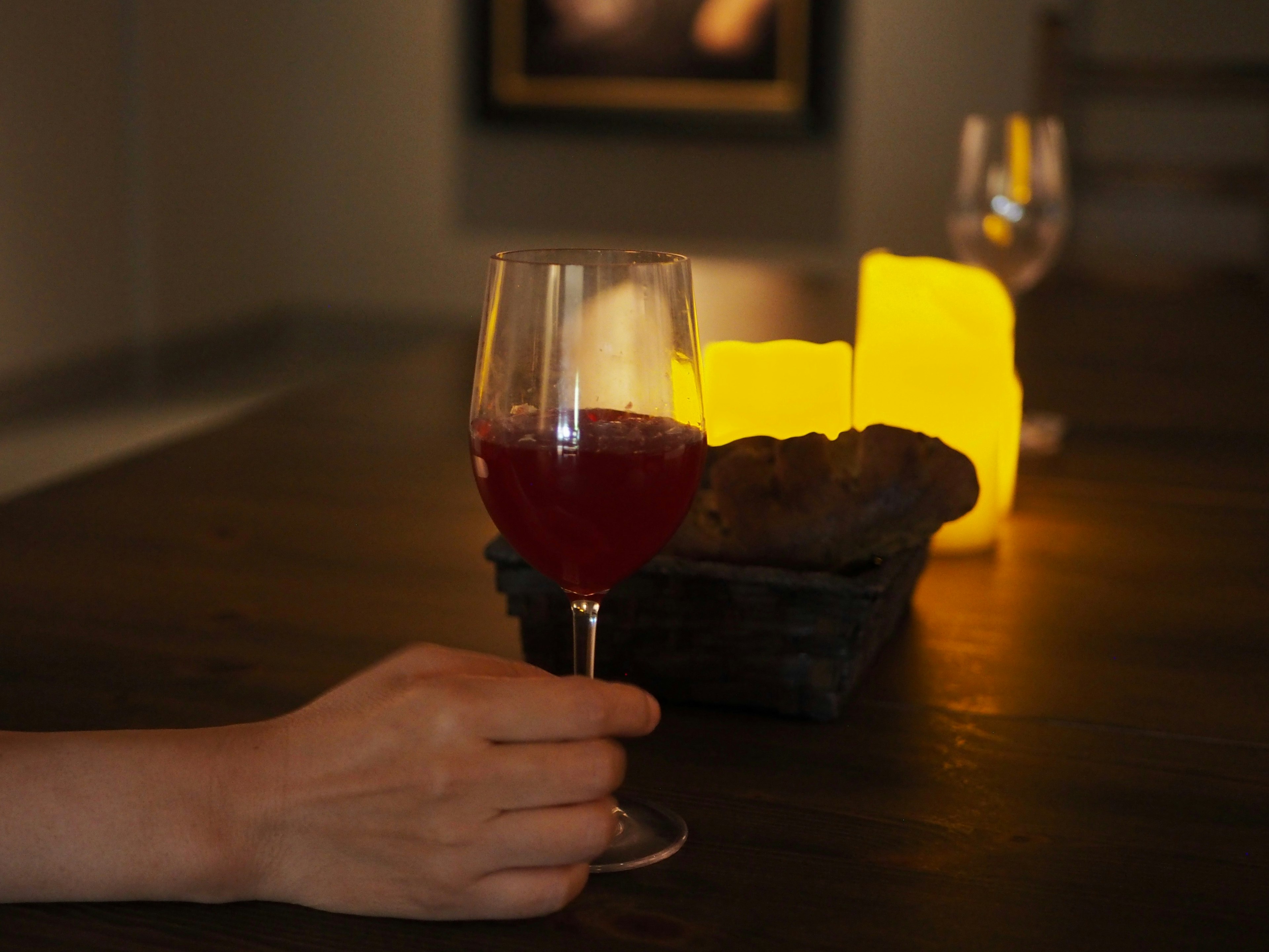 Ein Glas mit rotem Getränk auf einem Tisch mit leuchtenden Kerzen