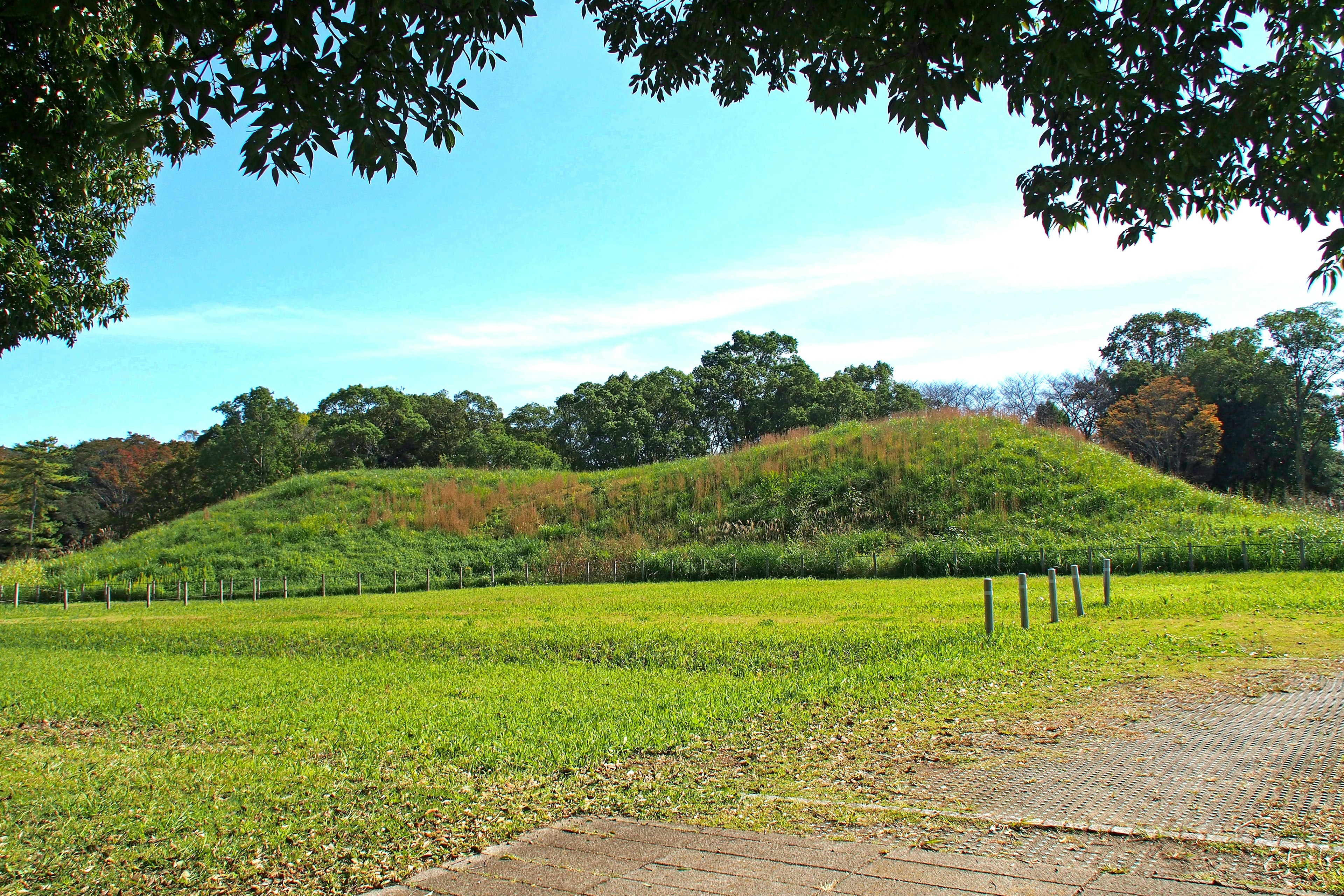 Landscape featuring a grassy burial mound under a clear blue sky