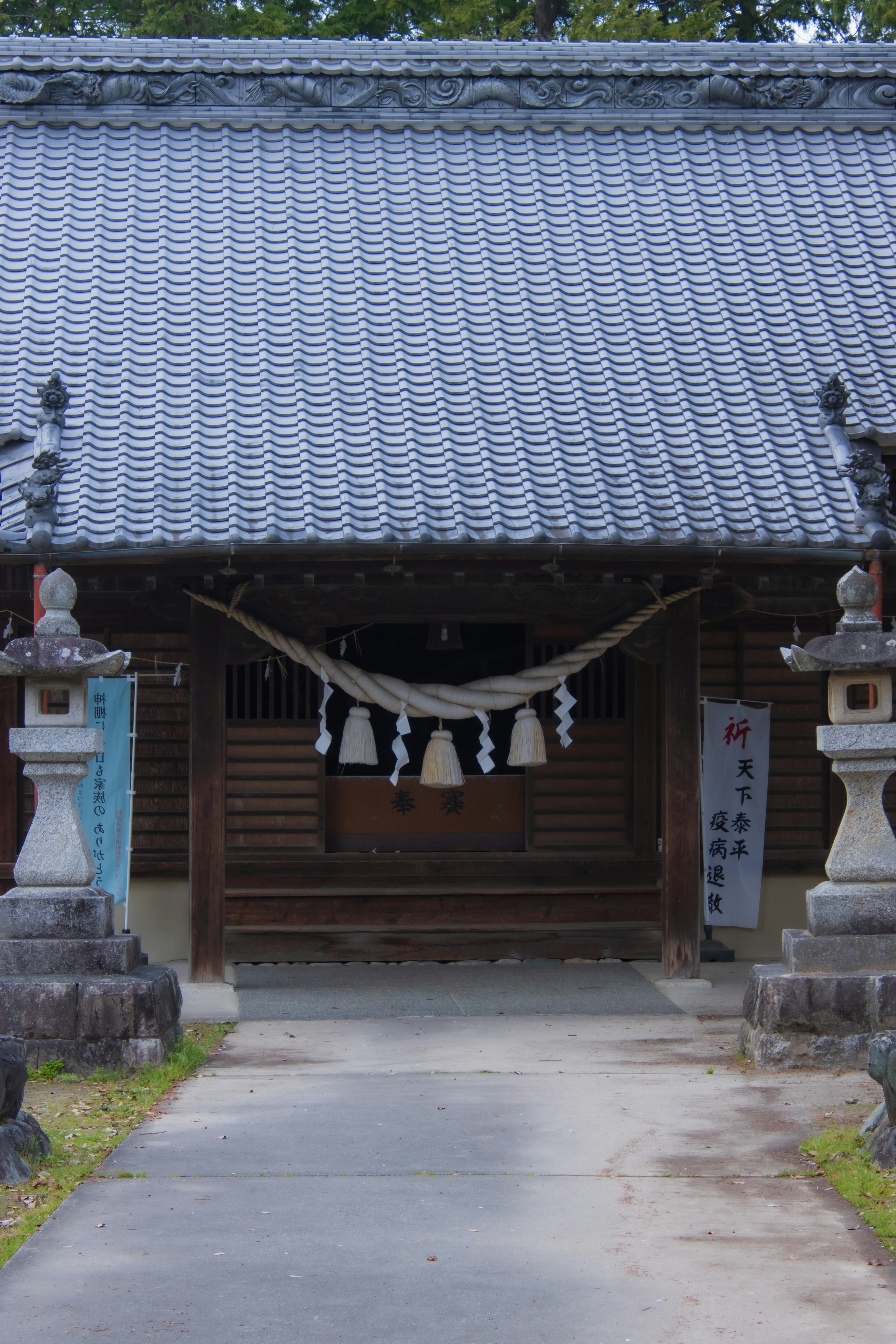 Entrée d'un temple japonais traditionnel avec un toit en tuiles et des lanternes en pierre