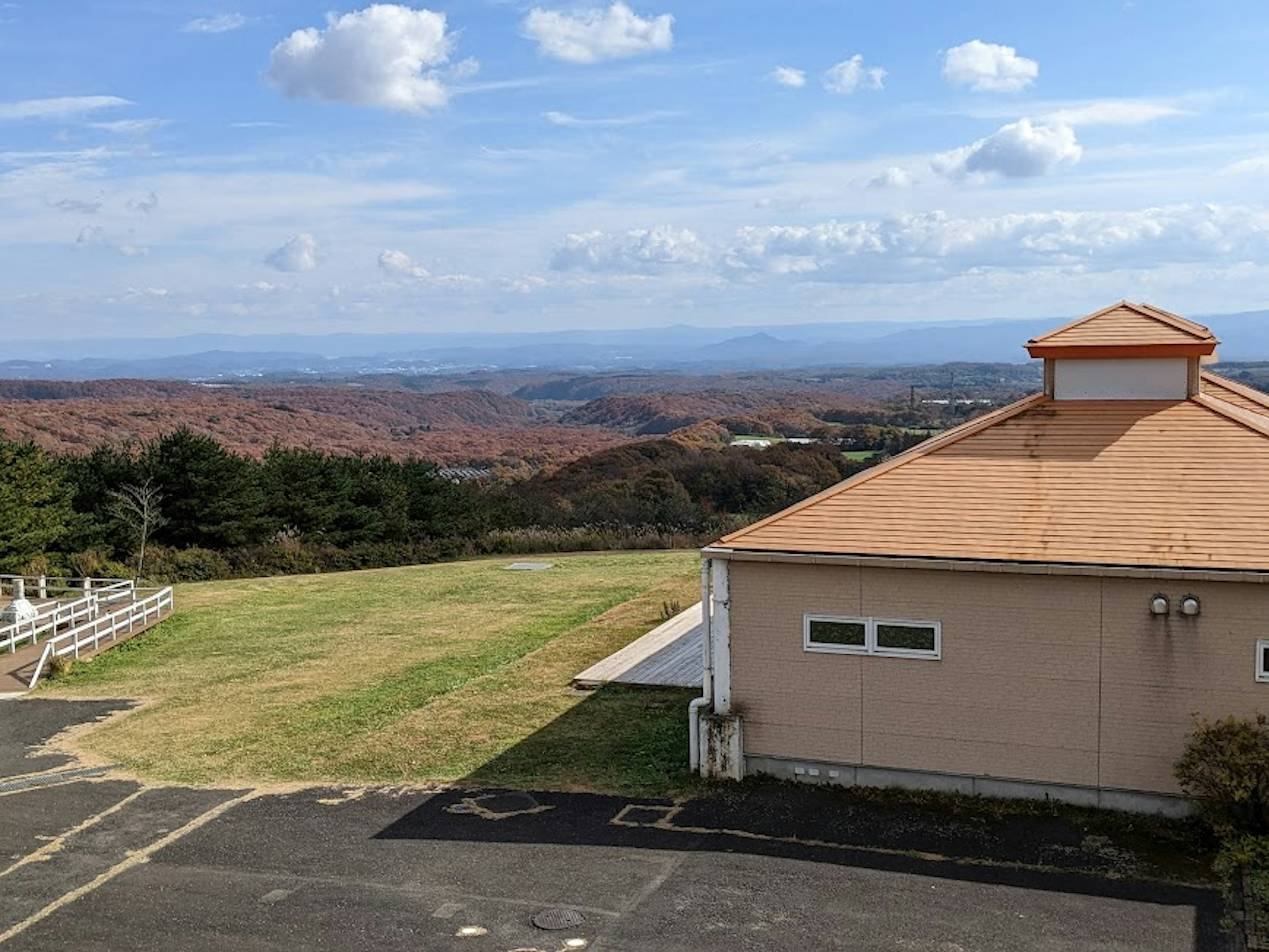 Scenic view from a hilltop featuring a building and expansive landscape