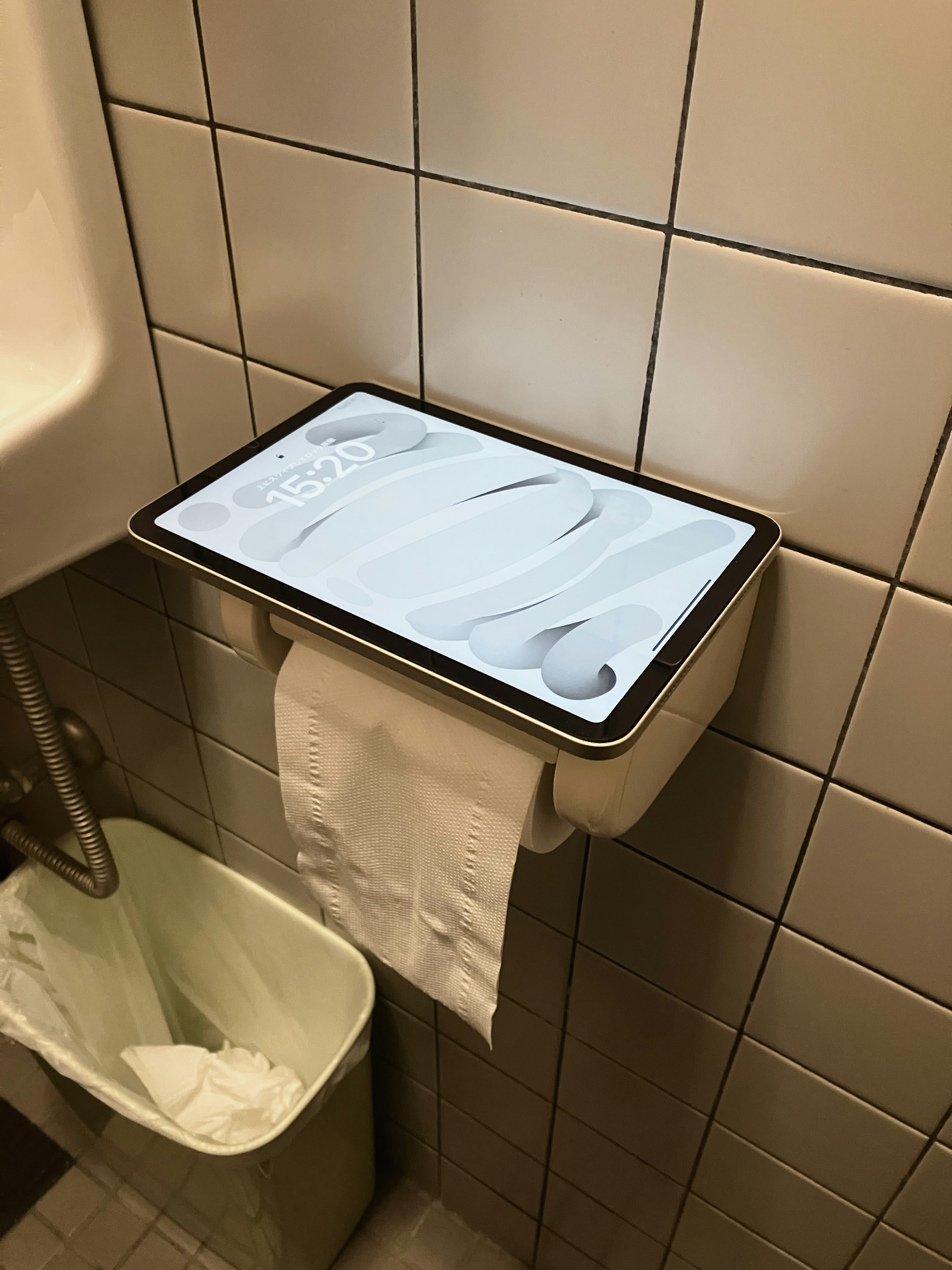 Tablet placed on top of a paper towel dispenser in a restroom