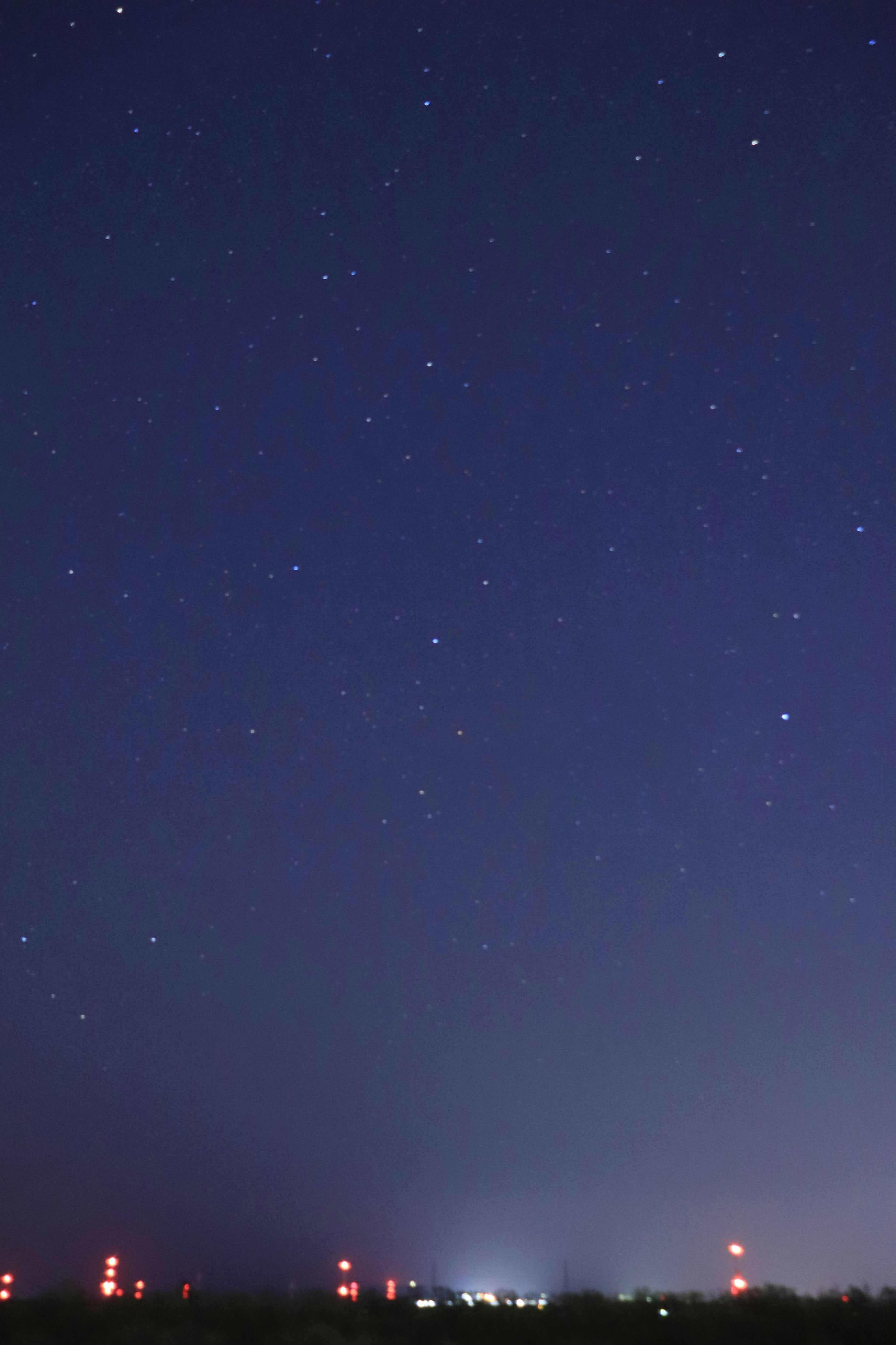 Night sky filled with stars and red lights in the landscape