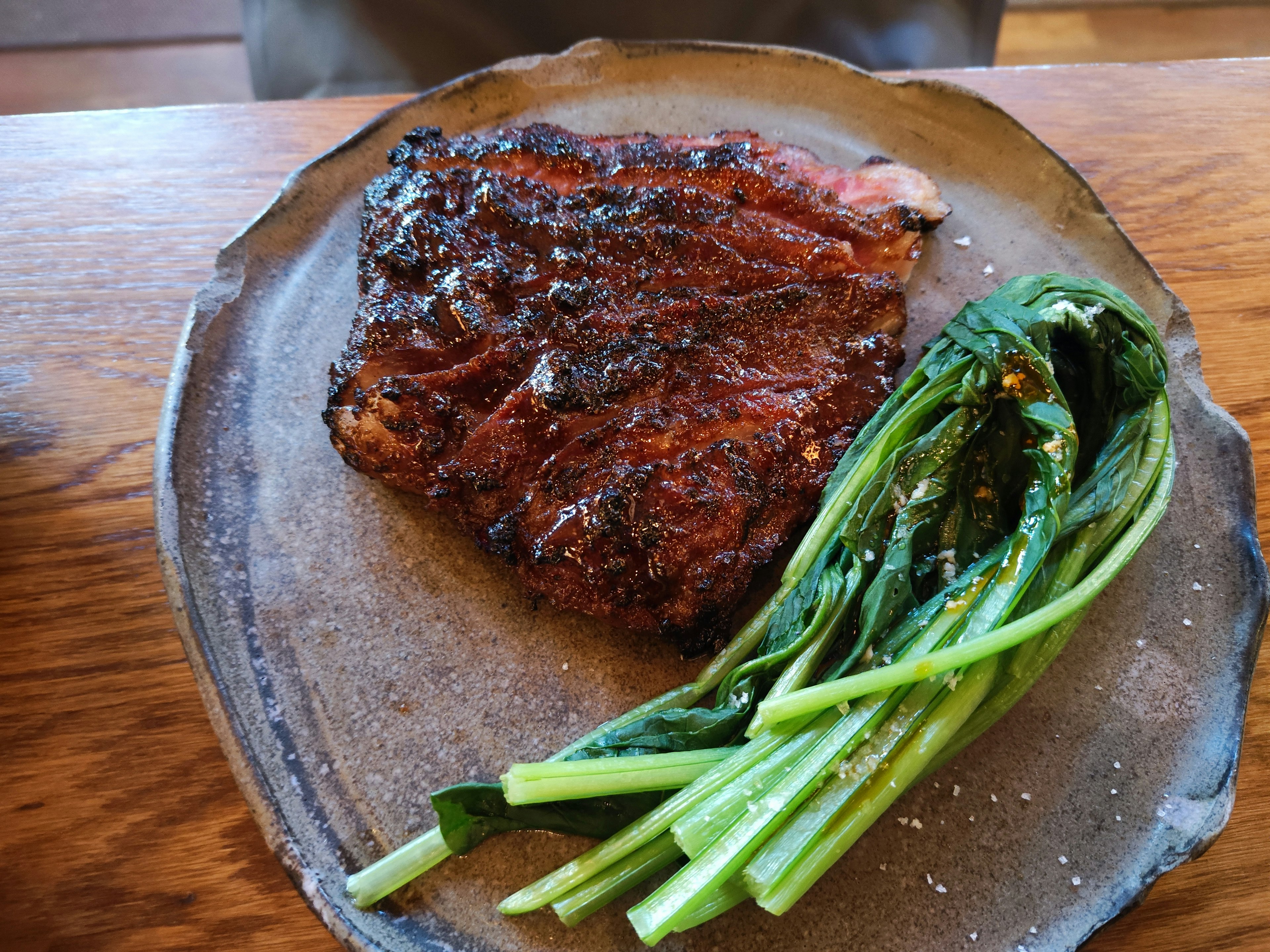 Gegrilltes Steak mit Frühlingszwiebeln auf einem rustikalen Teller