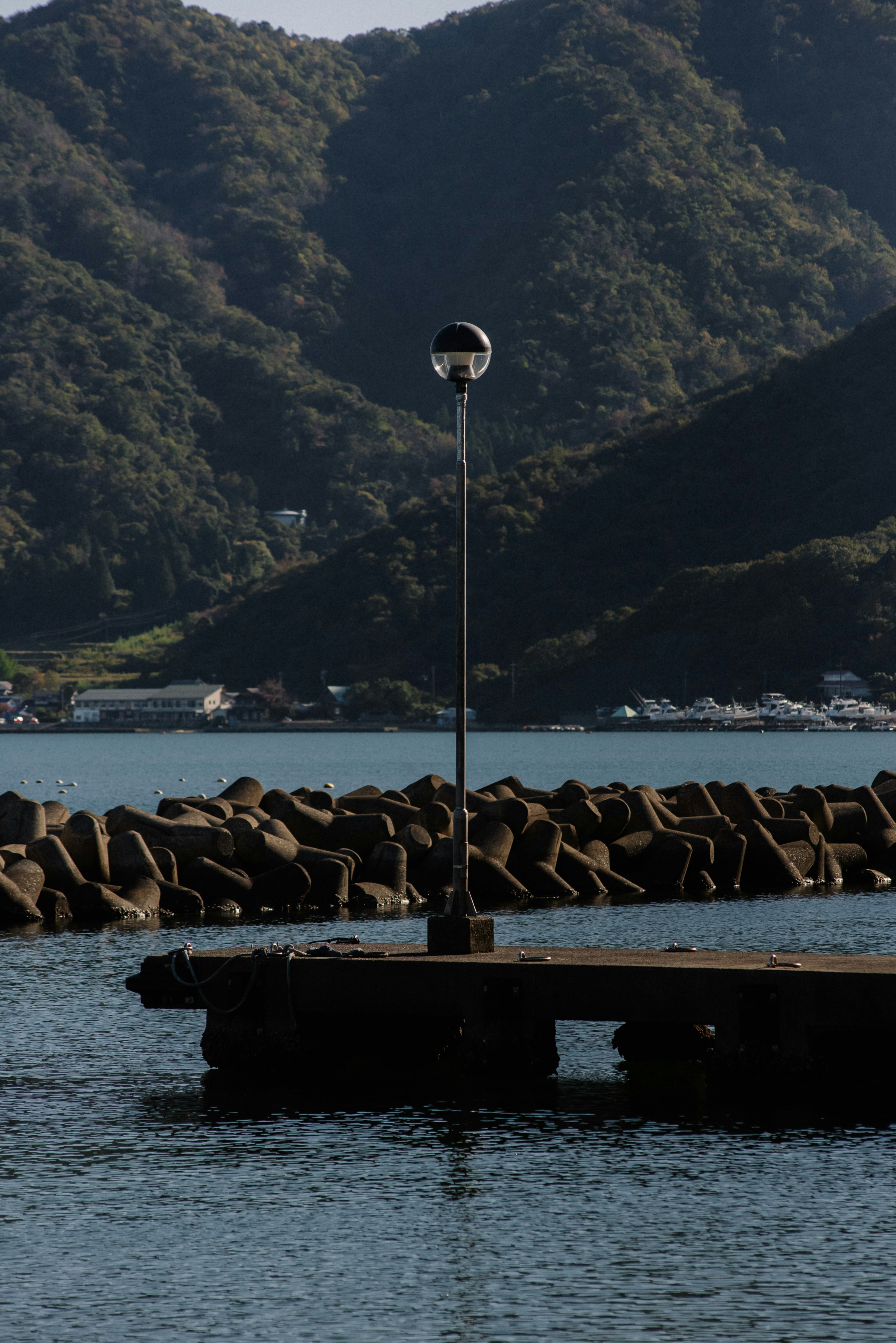 Molo sull'acqua con un faro e uno sfondo montagnoso