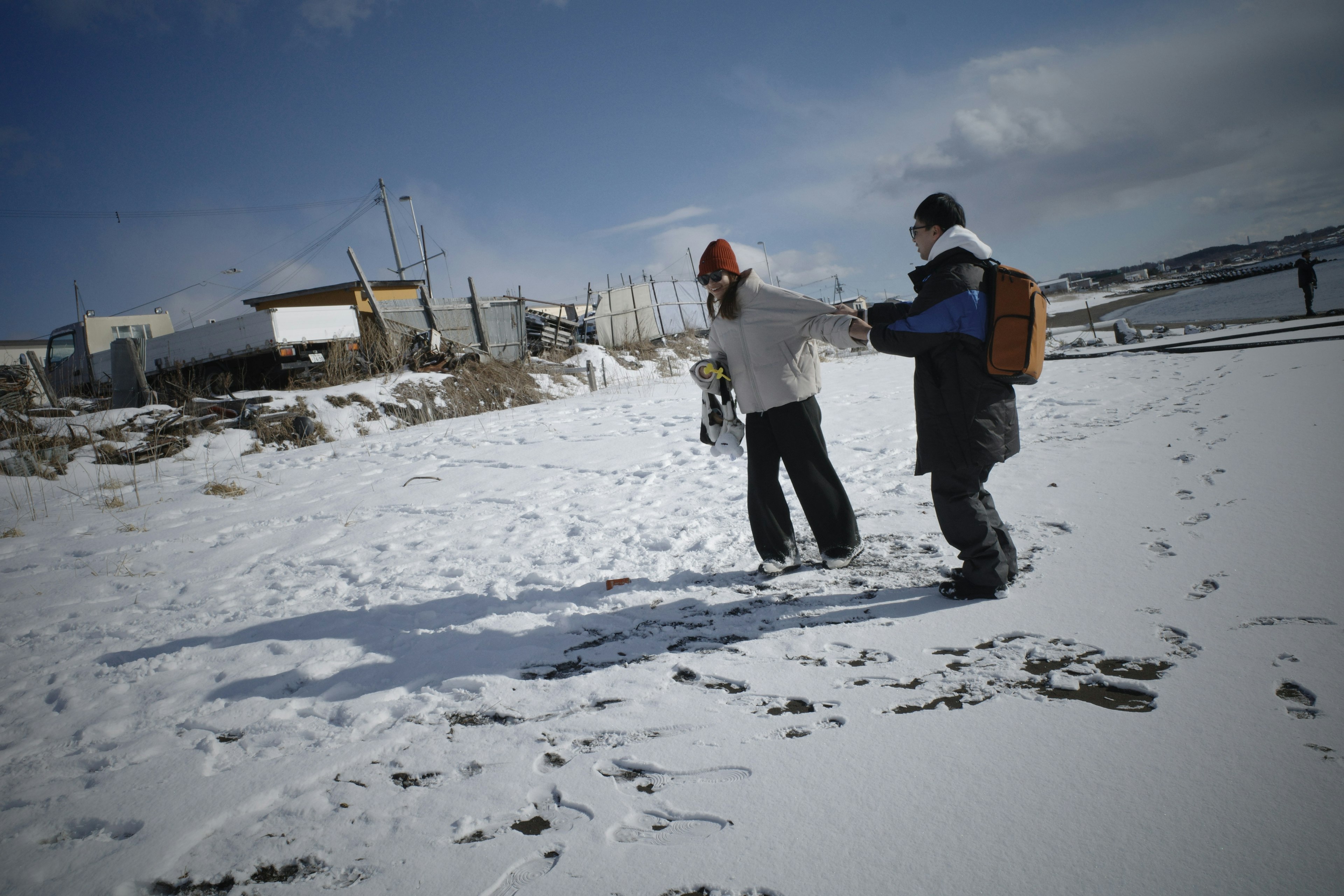 Two people walking on snow with a bright blue sky