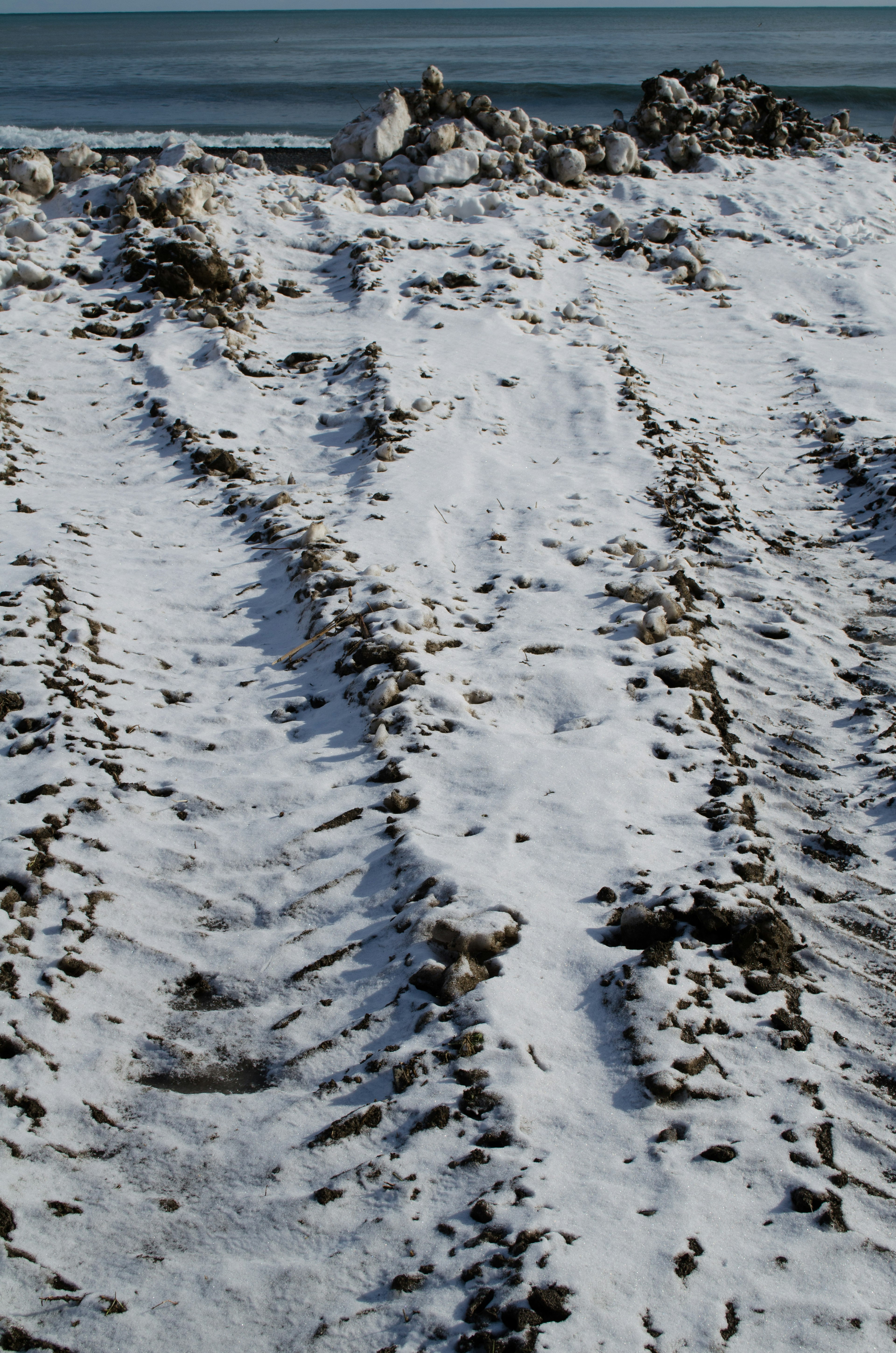 Tire tracks on a snow-covered ground with stones