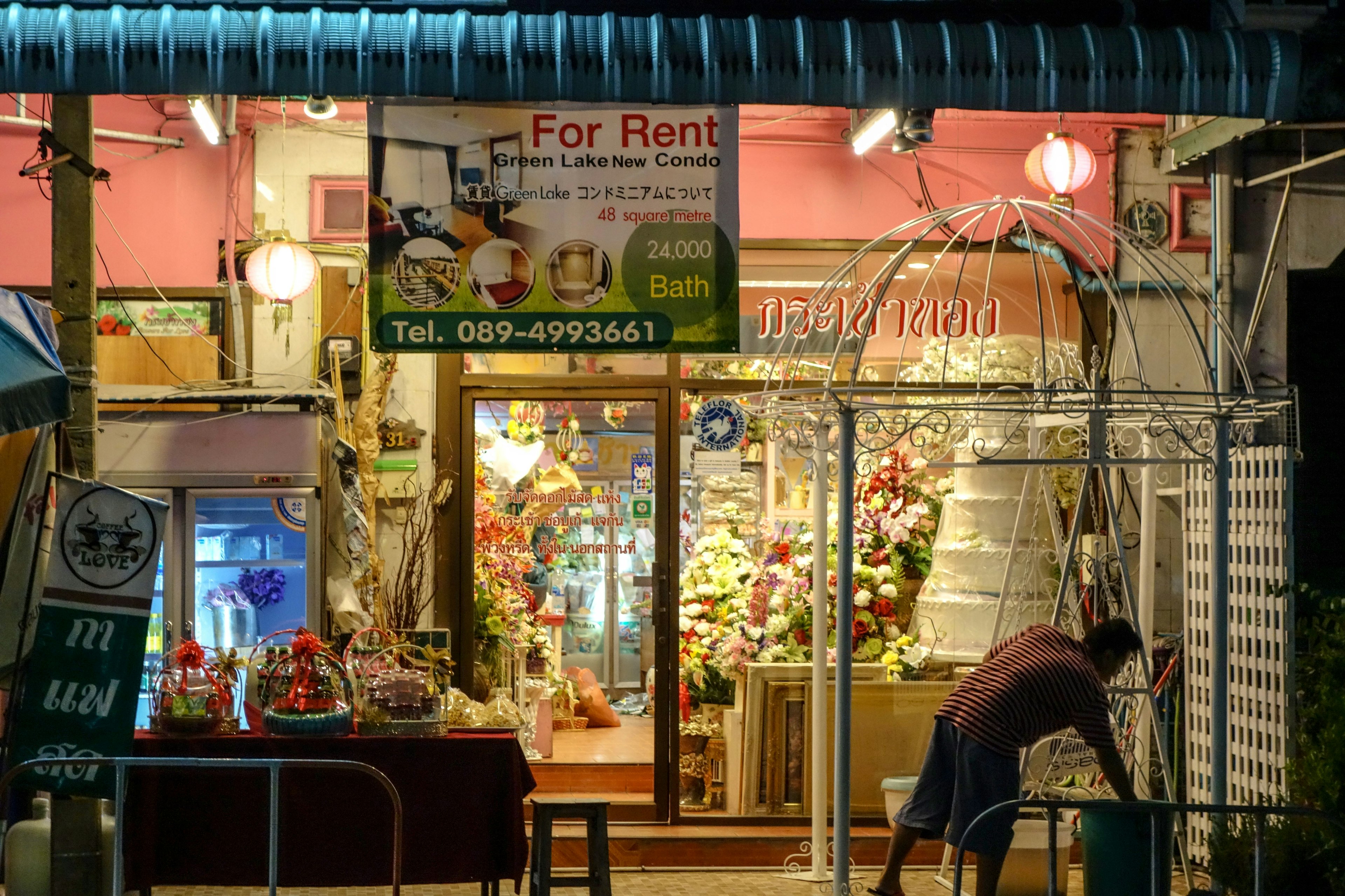 Vitrine colorée avec des fleurs et décorations visibles à l'extérieur la nuit