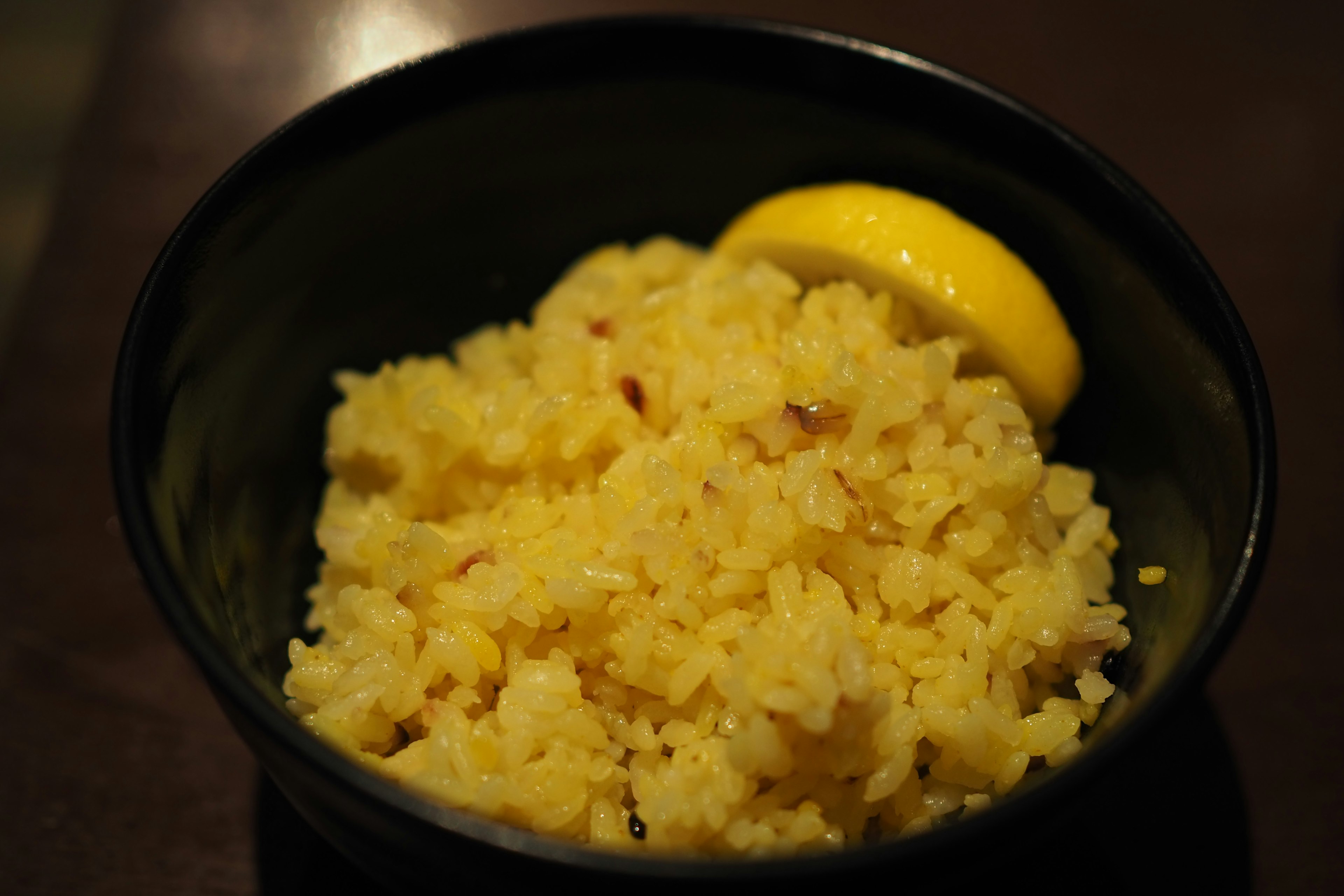 黄色いご飯のボウルにレモンのスライスが添えられています