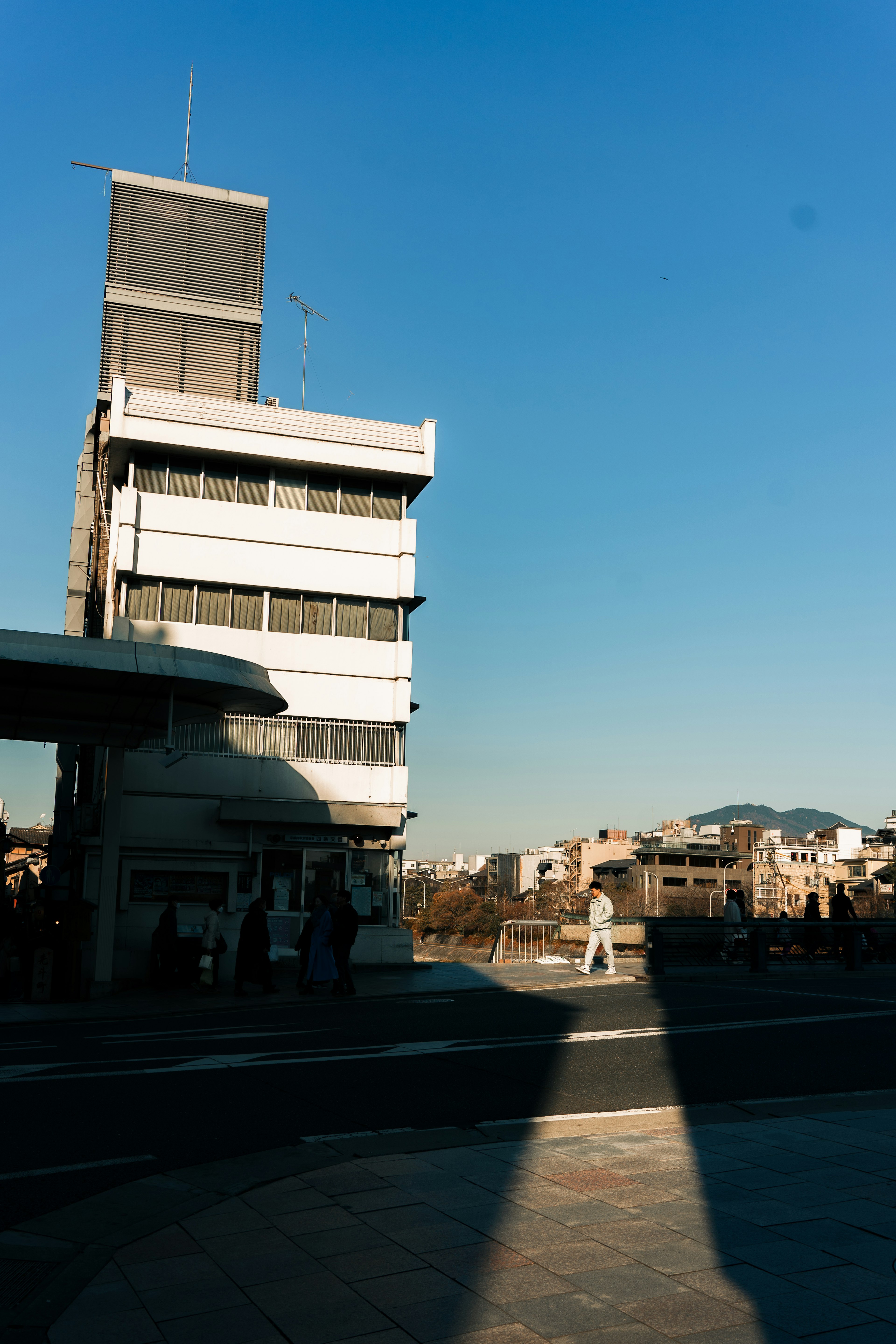 A white building casting a shadow under a clear blue sky