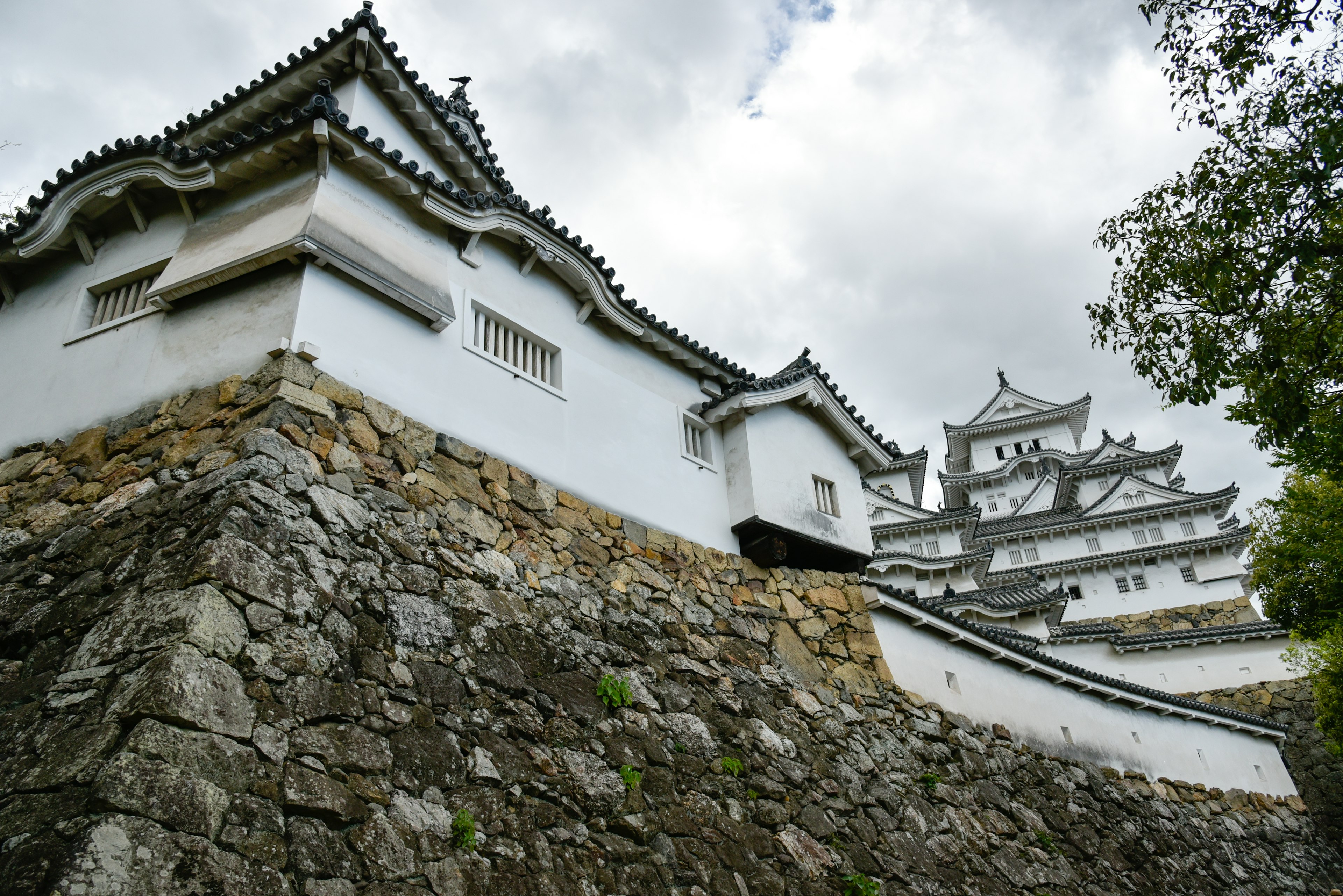 Vue latérale du château de Himeji montrant des murs blancs et des fondations en pierre