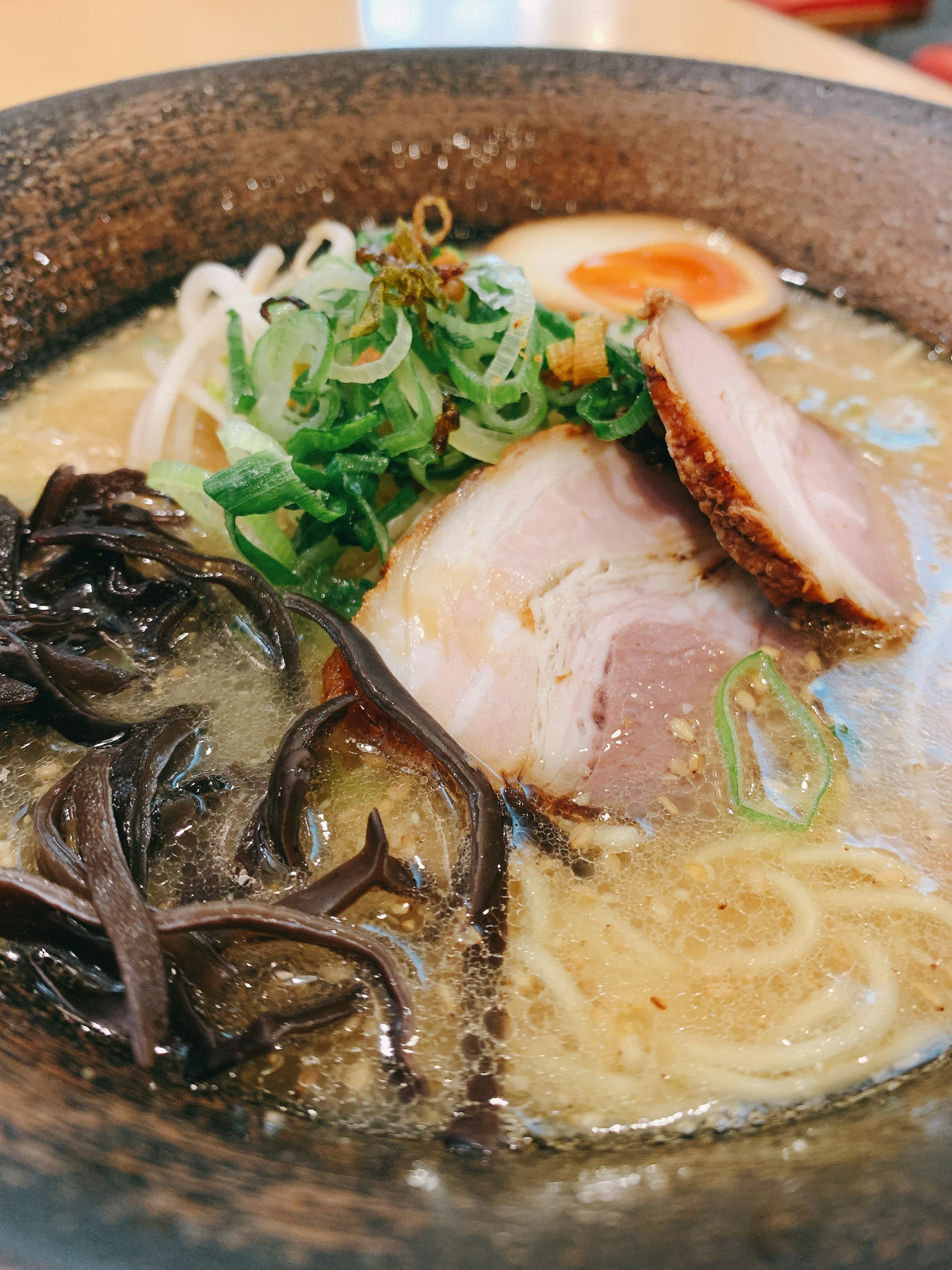 Mangkuk ramen dengan irisan chashu, daun bawang, dan telur setengah matang