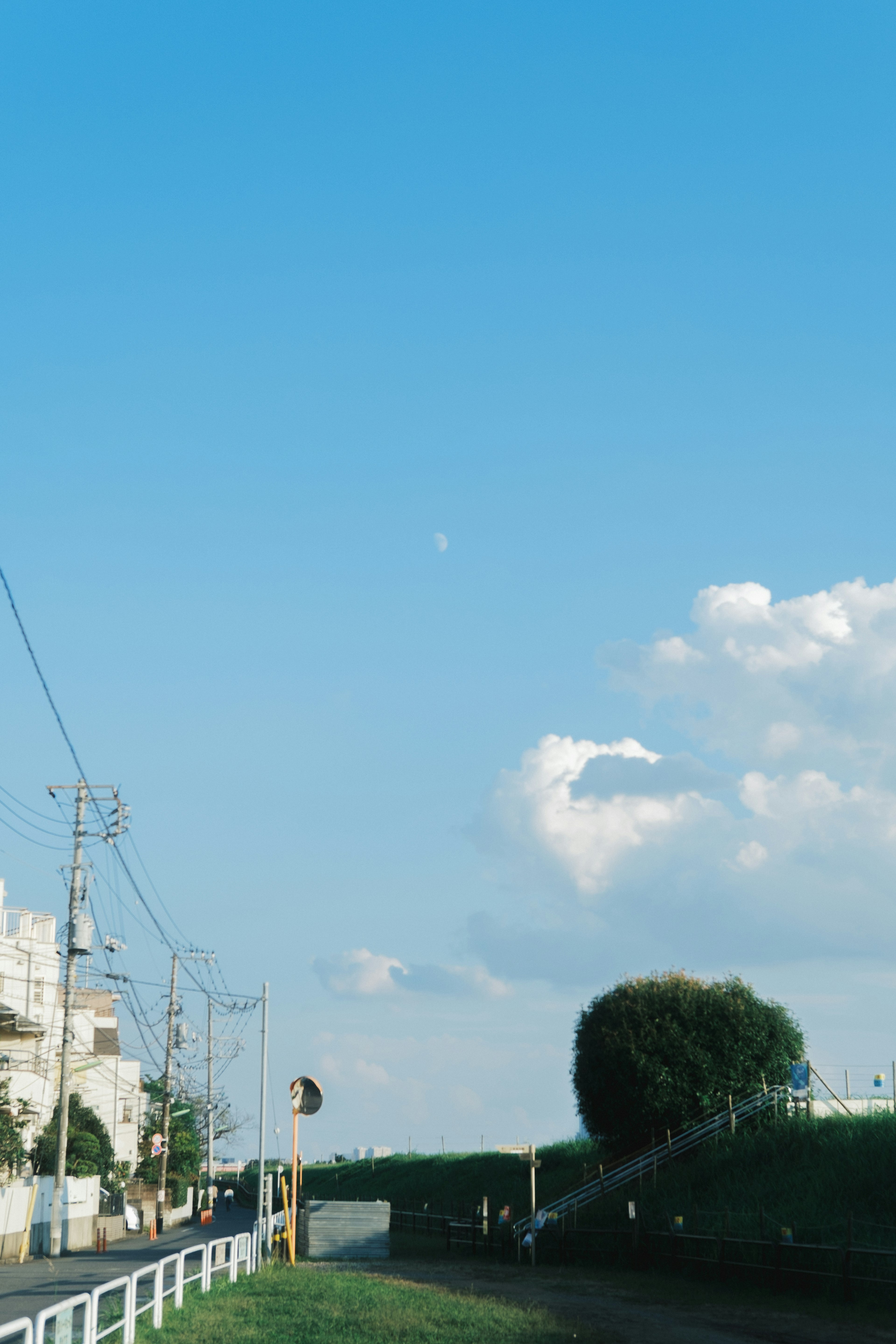 Paisaje con nubes blancas y luna en un cielo azul