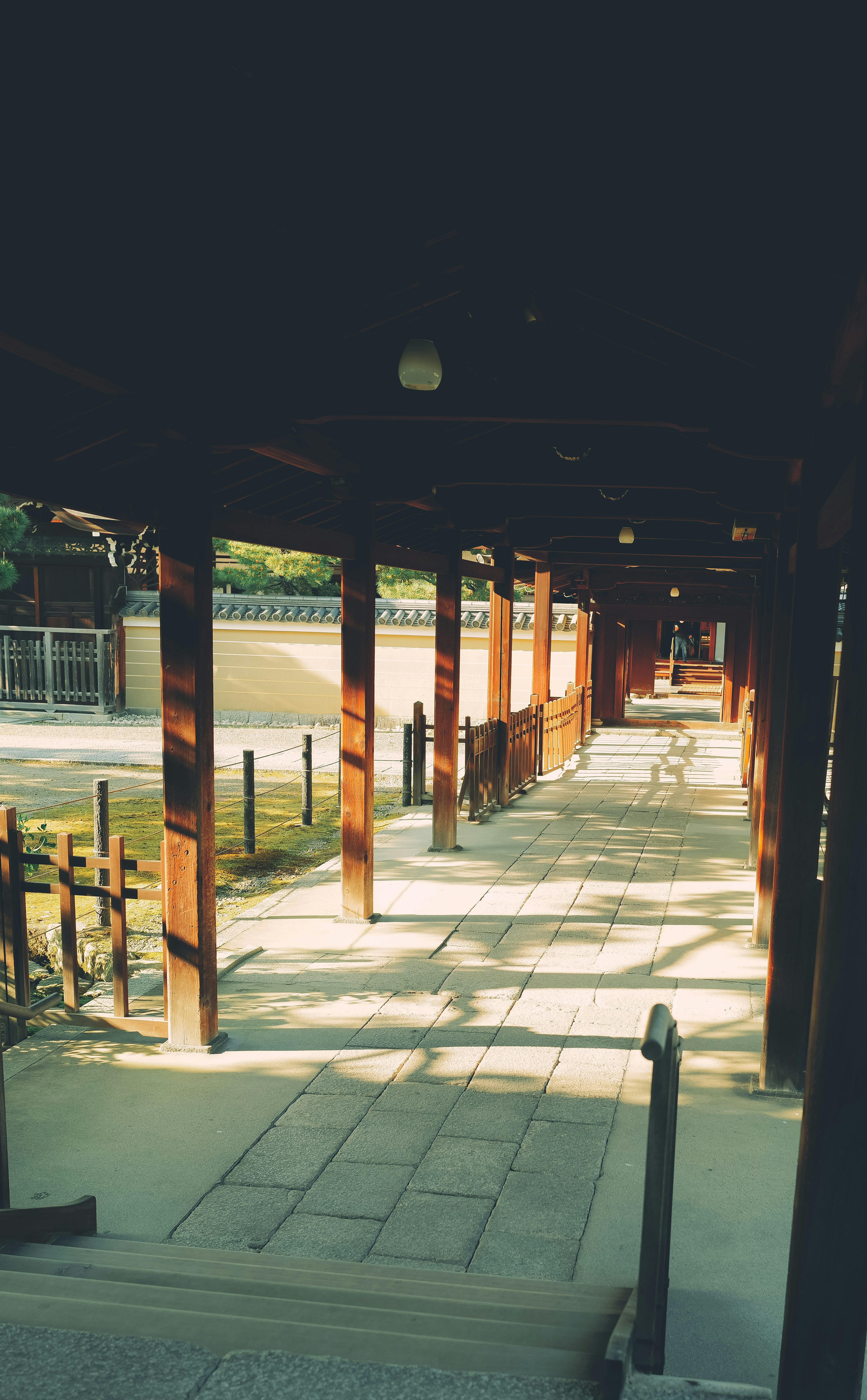 A long corridor supported by wooden pillars with sunlight filtering through