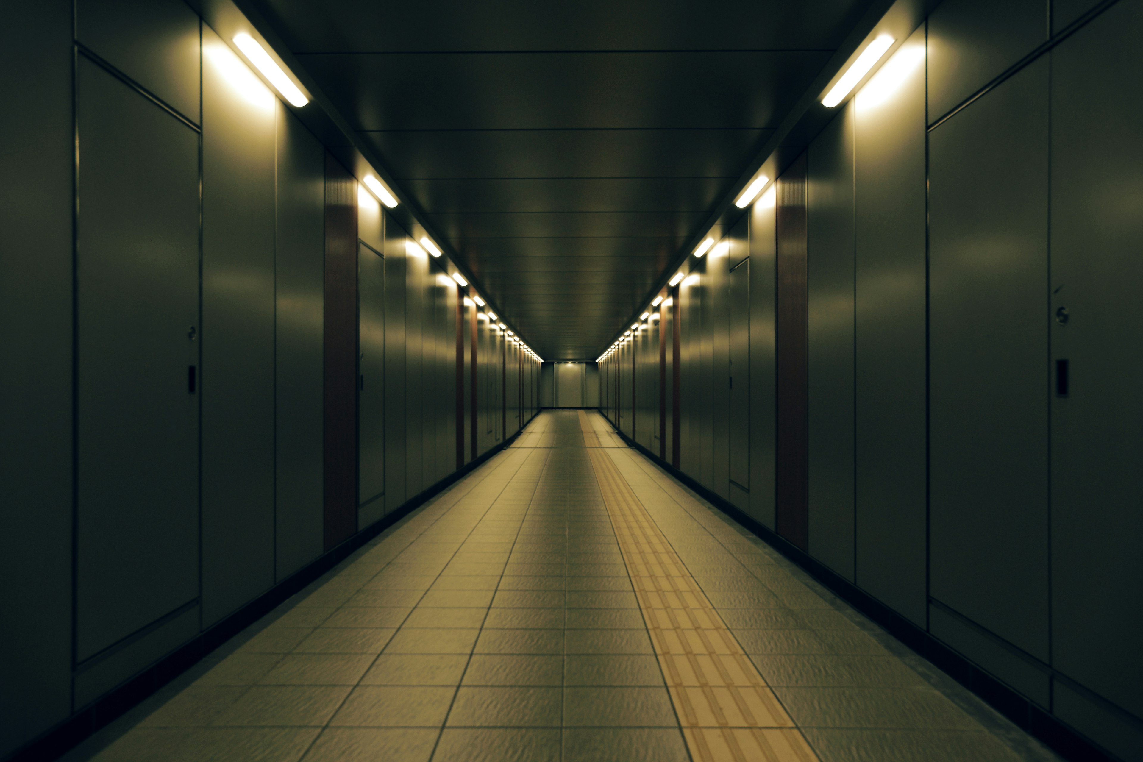 Long dark corridor leading to a bright end with tiled floor