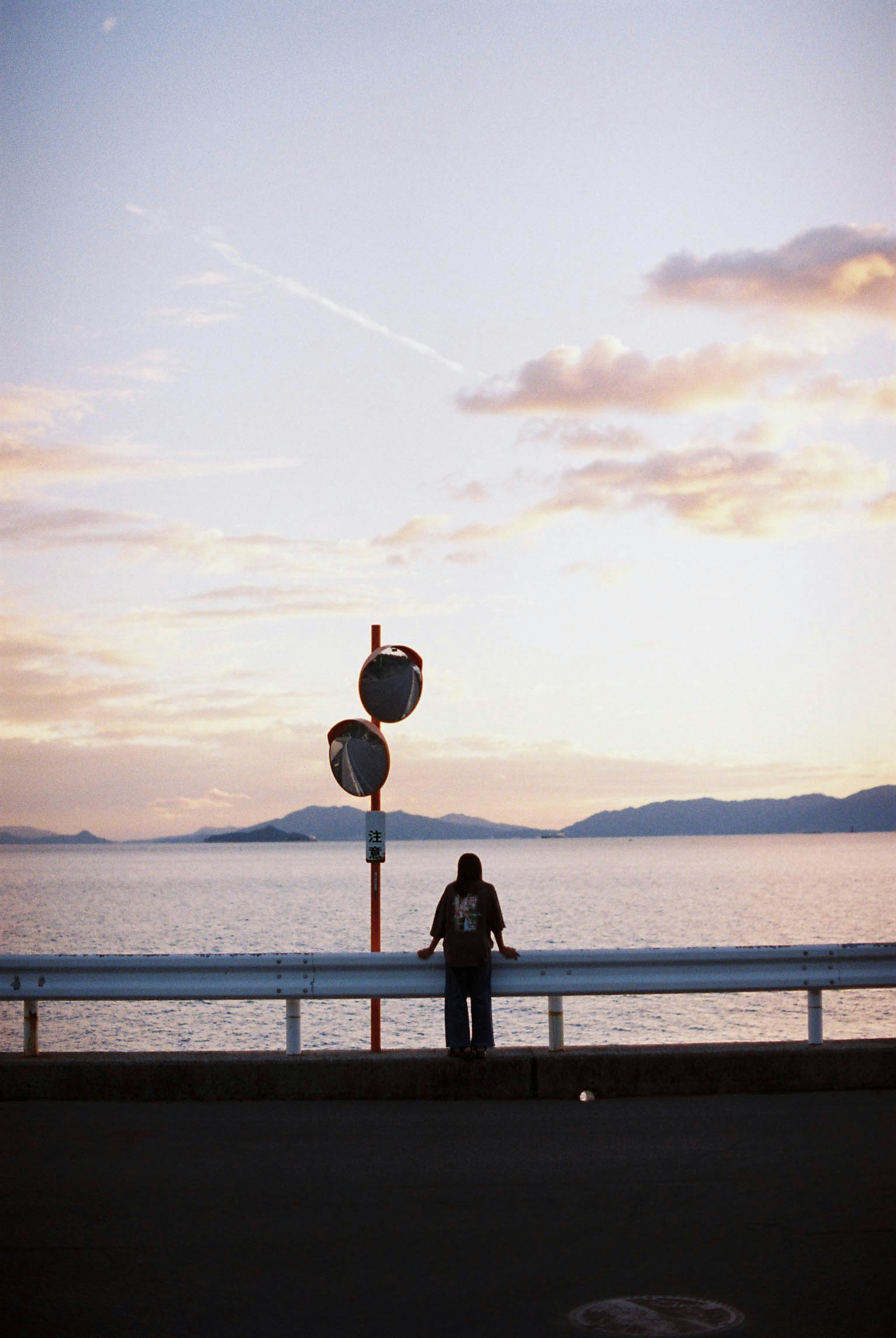 Persona de pie junto al mar al atardecer con señalización